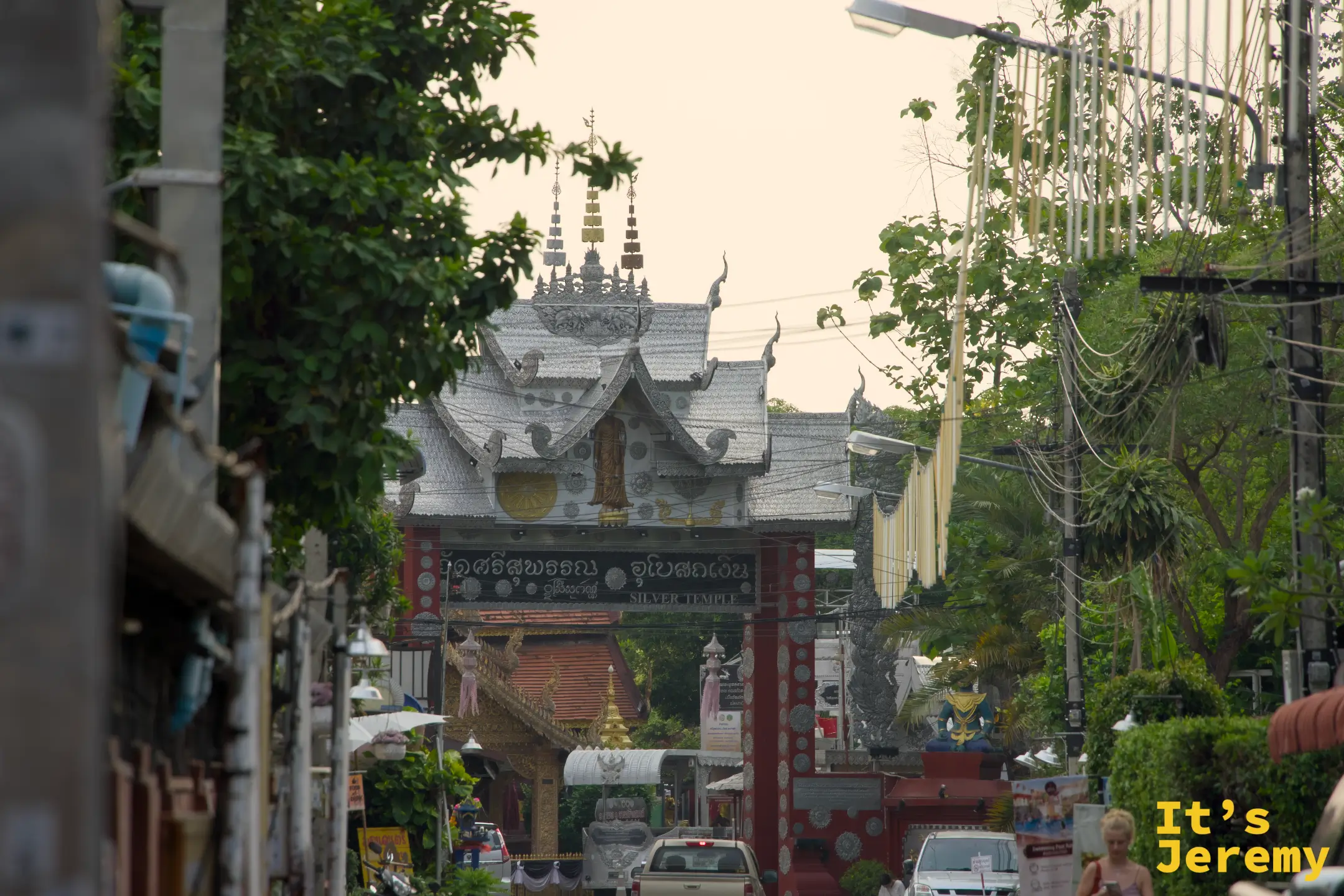 從更遠的角度看入口，整條 วัวลาย 路的銀器店招牌包圍著銀殿入口
