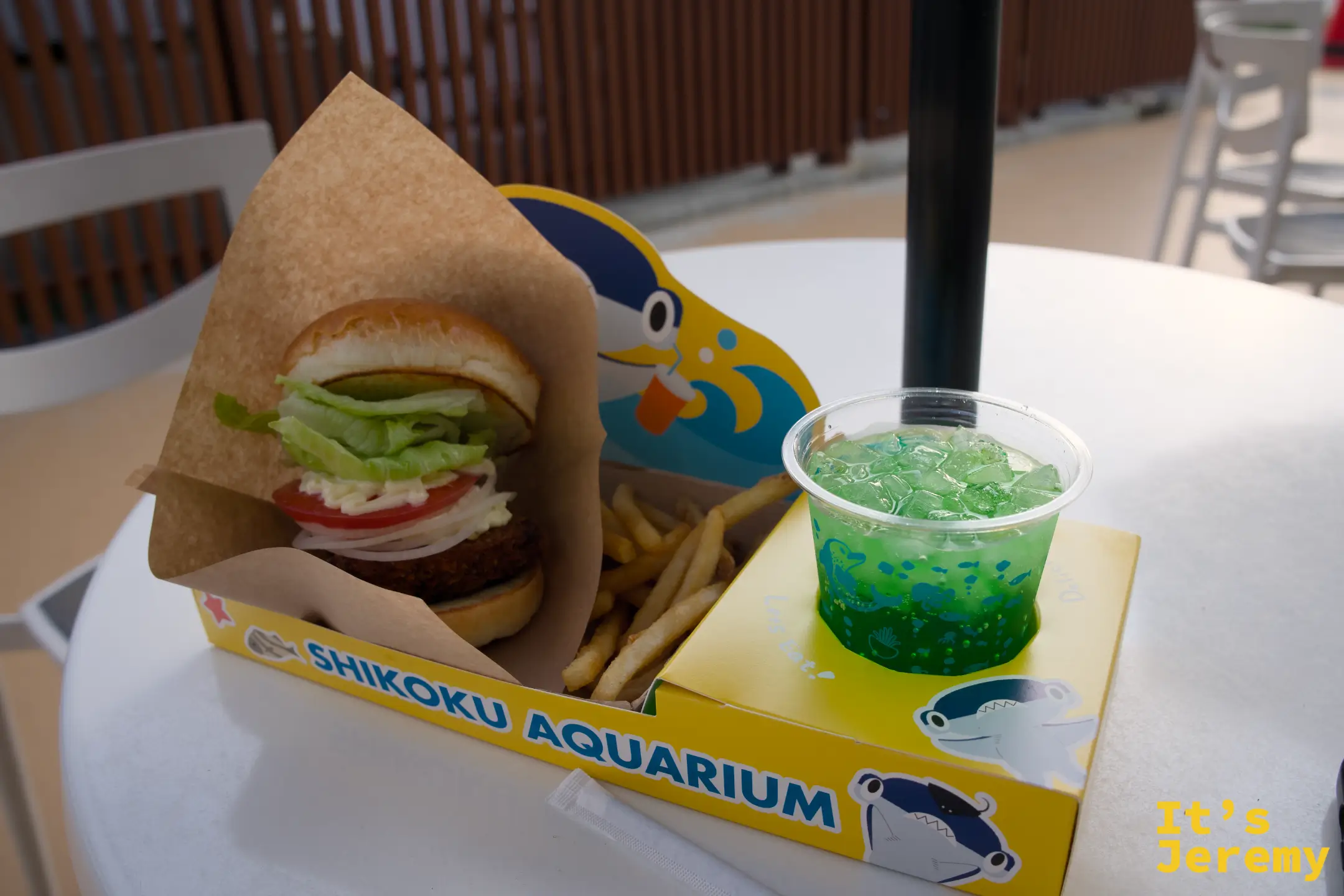 Shikoku Aquarium 主題漢堡套餐，漢堡加薯條放在黃色紙盒裡，旁邊是綠色碎冰飲料