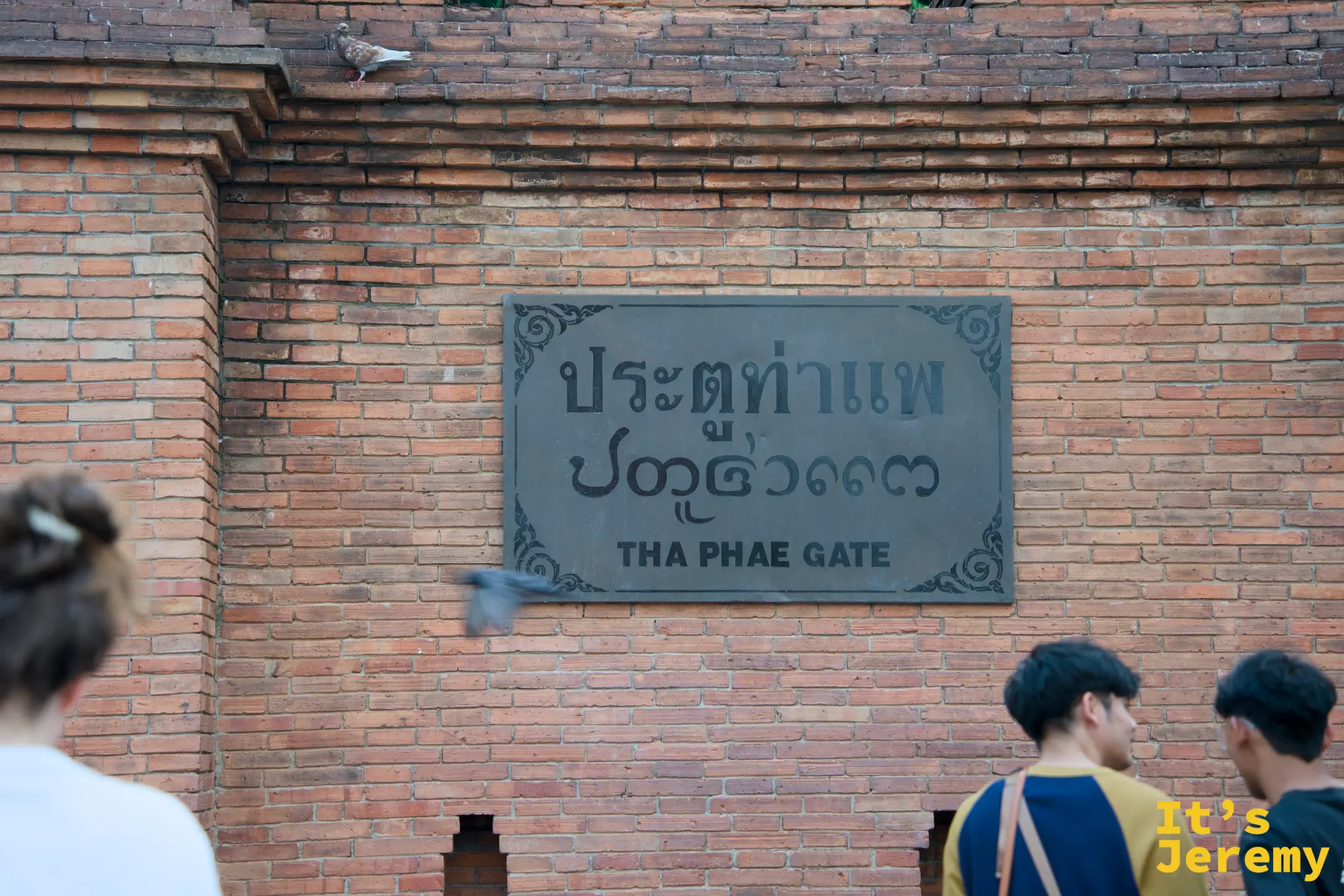 城牆上的塔佩門銘牌，泰文與英文並列：THA PHAE GATE