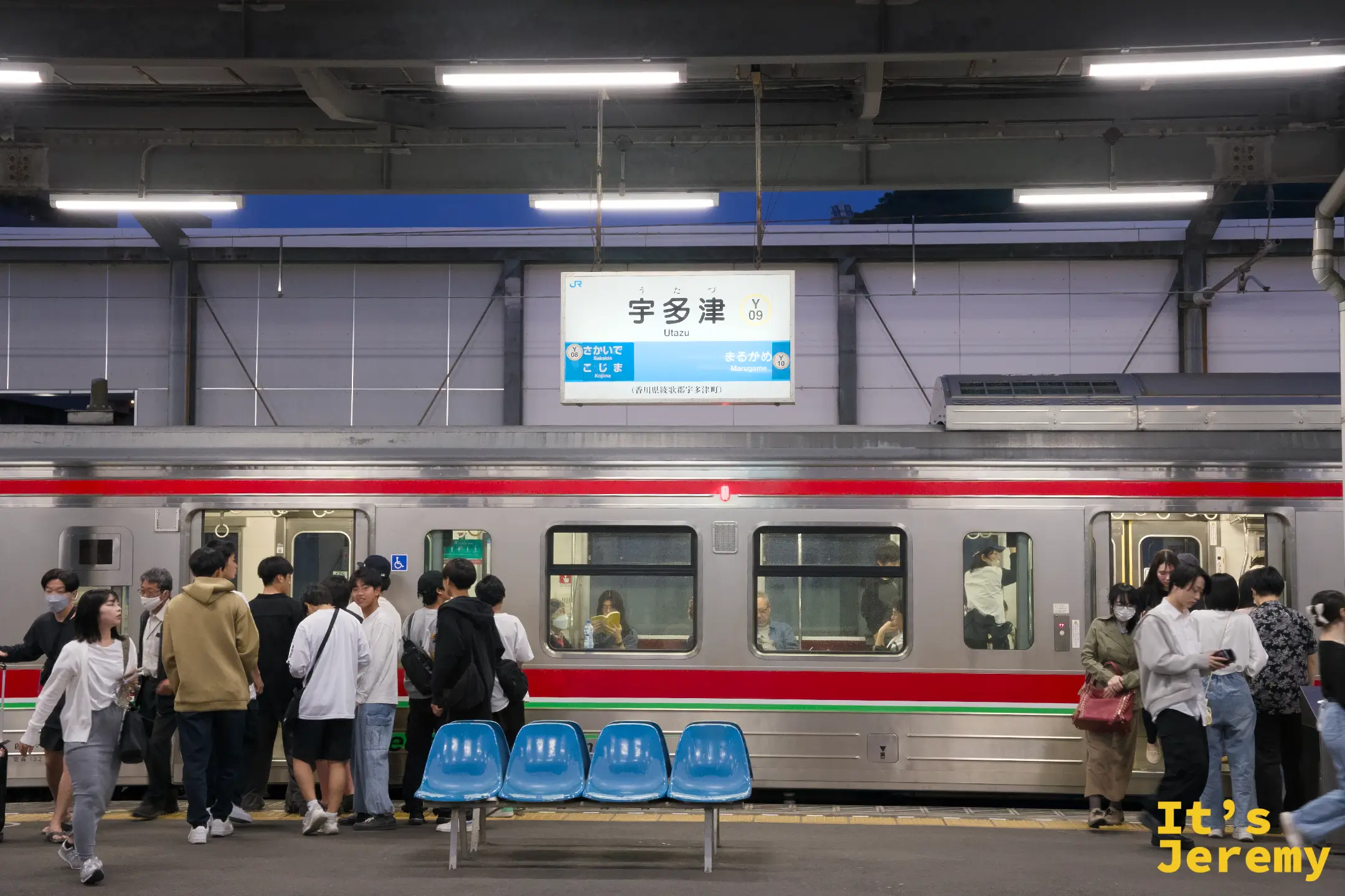 宇多津站（Y09）月台夜景，燈光打亮站名牌，乘客密集地在月台等待上下車