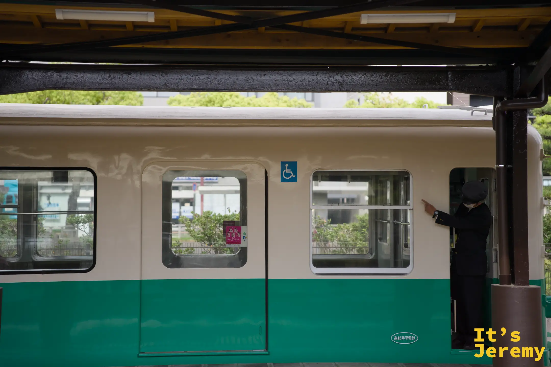 琴電車廂停靠月台，米色搭配綠色腰帶塗裝，站務員側身確認車門