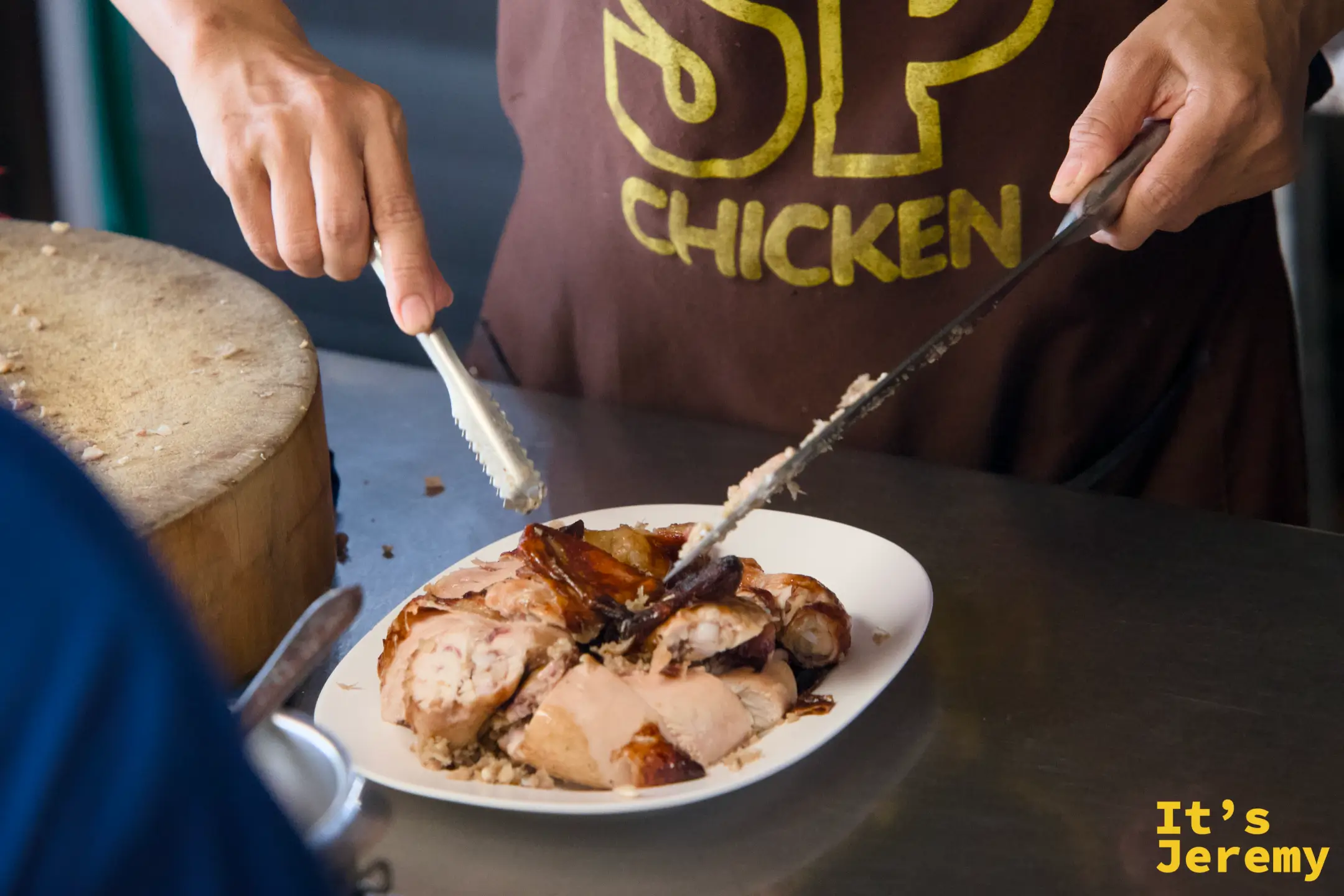 SP Chicken 圍裙師傅正在把切好的烤雞裝盤，動作俐落