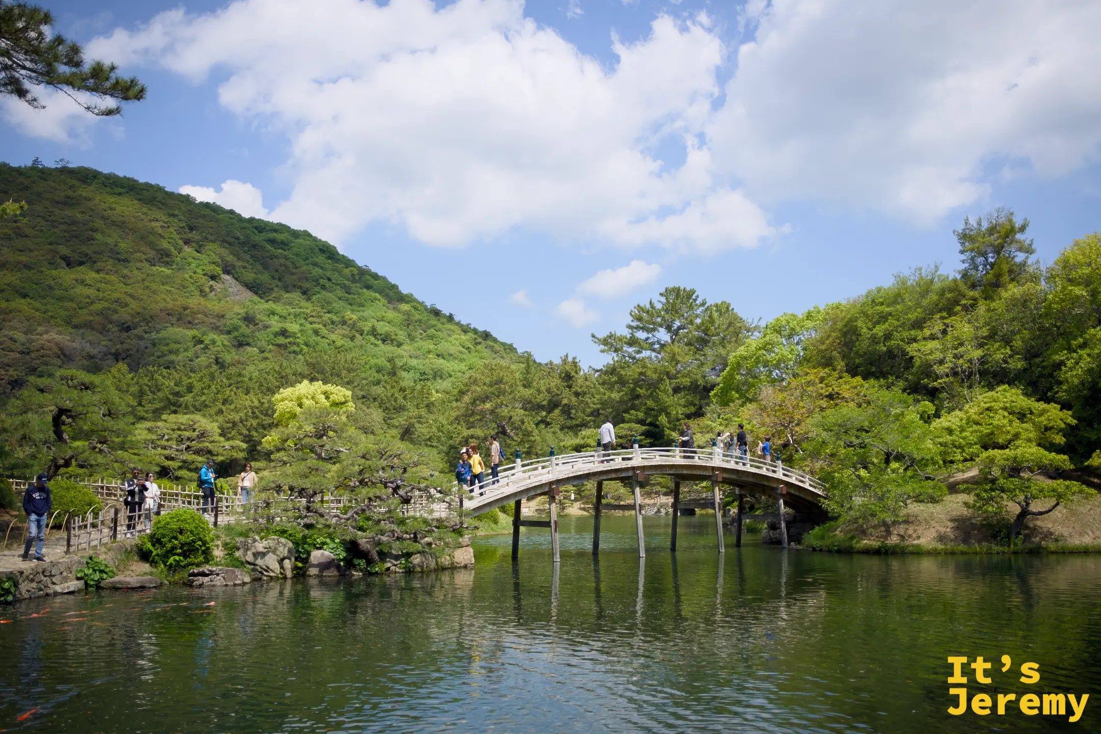 偃月橋全景，白色半月形石拱橋橫跨南湖，背景是紫雲山的綠色山體與藍天