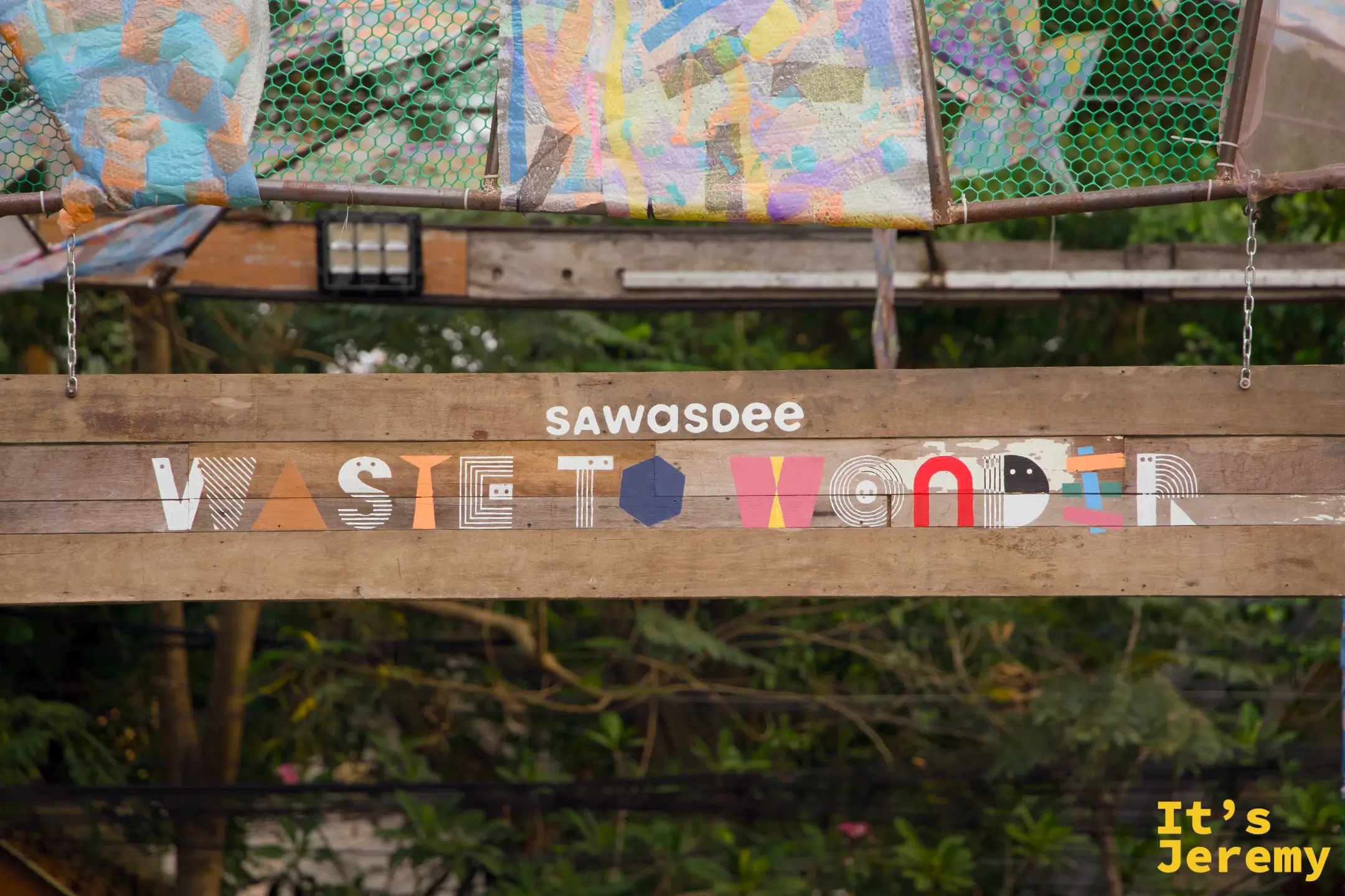 廊架主梁寫著「sawasdee WASTE TO WONDER」字樣，字母由彩色幾何圖形構成，充滿設計感