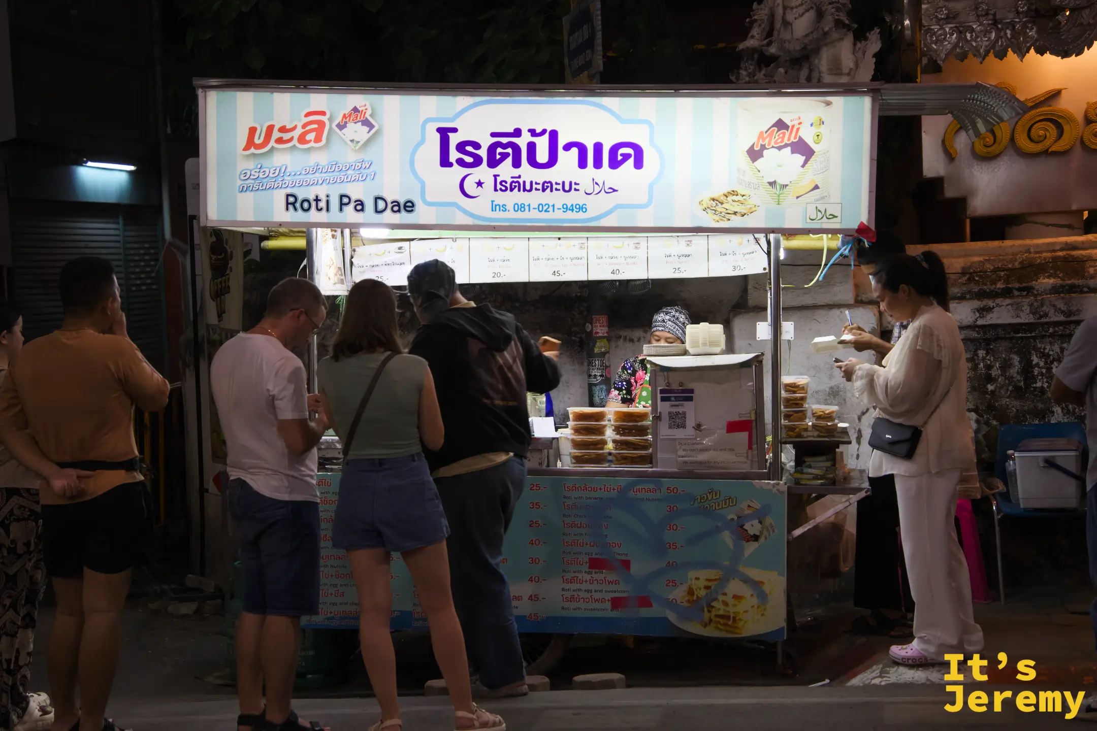 Roti Pa Dae 攤車正面，薄荷綠招牌寫著泰文店名與電話，攤前站滿等餐的客人