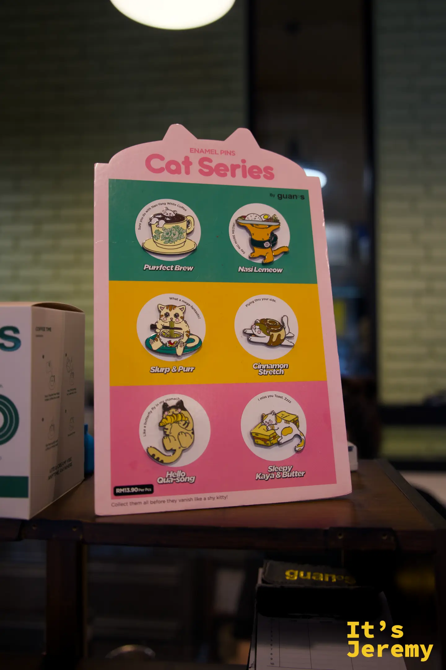 店內「Cat Series」貓咪主題琺瑯徽章的展示卡，粉紅、橘、綠色分格排列各款設計
