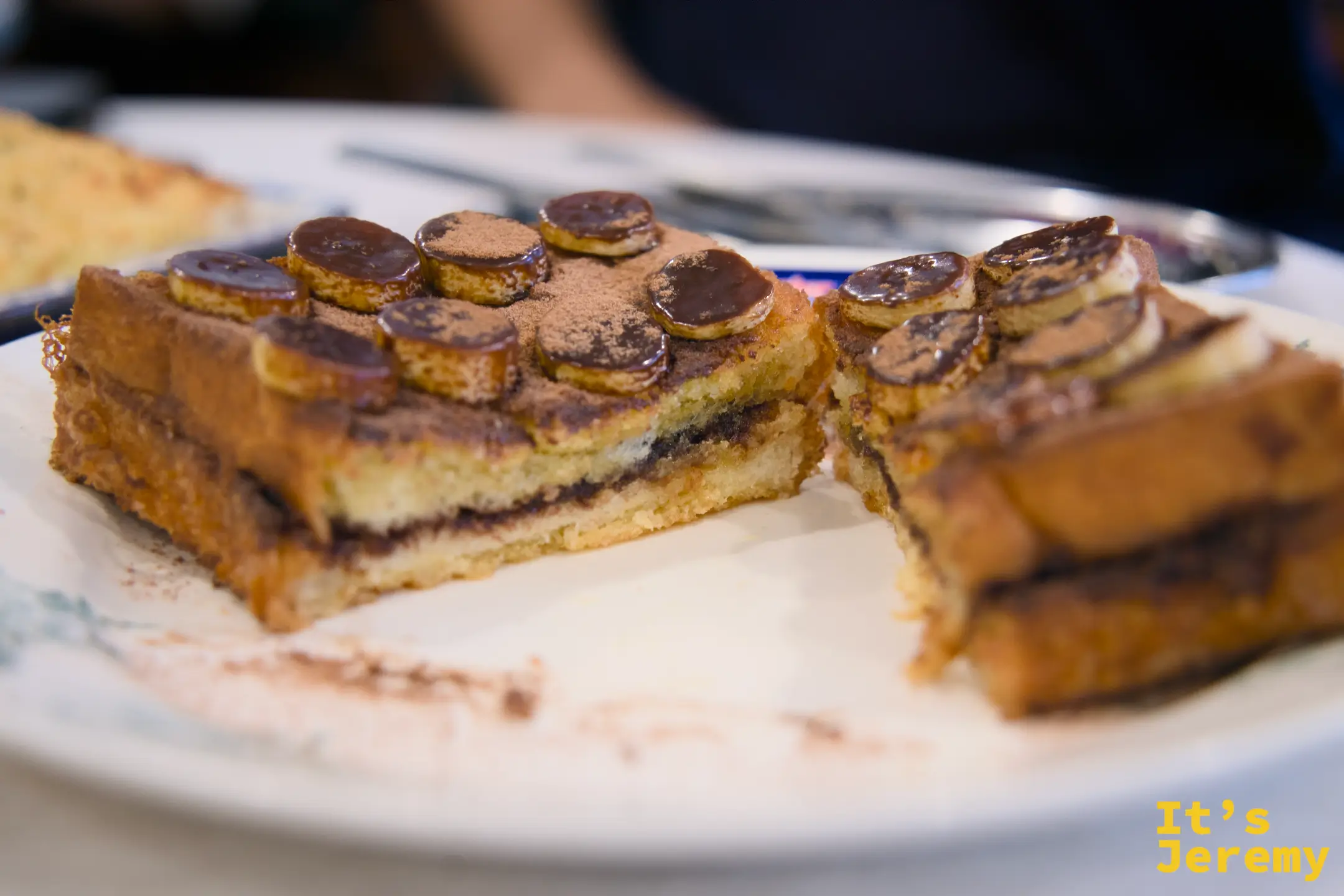 Nutella Banana French Toast 特寫，厚切吐司夾著 Nutella，表面鋪滿香蕉圓片並撒上可可粉