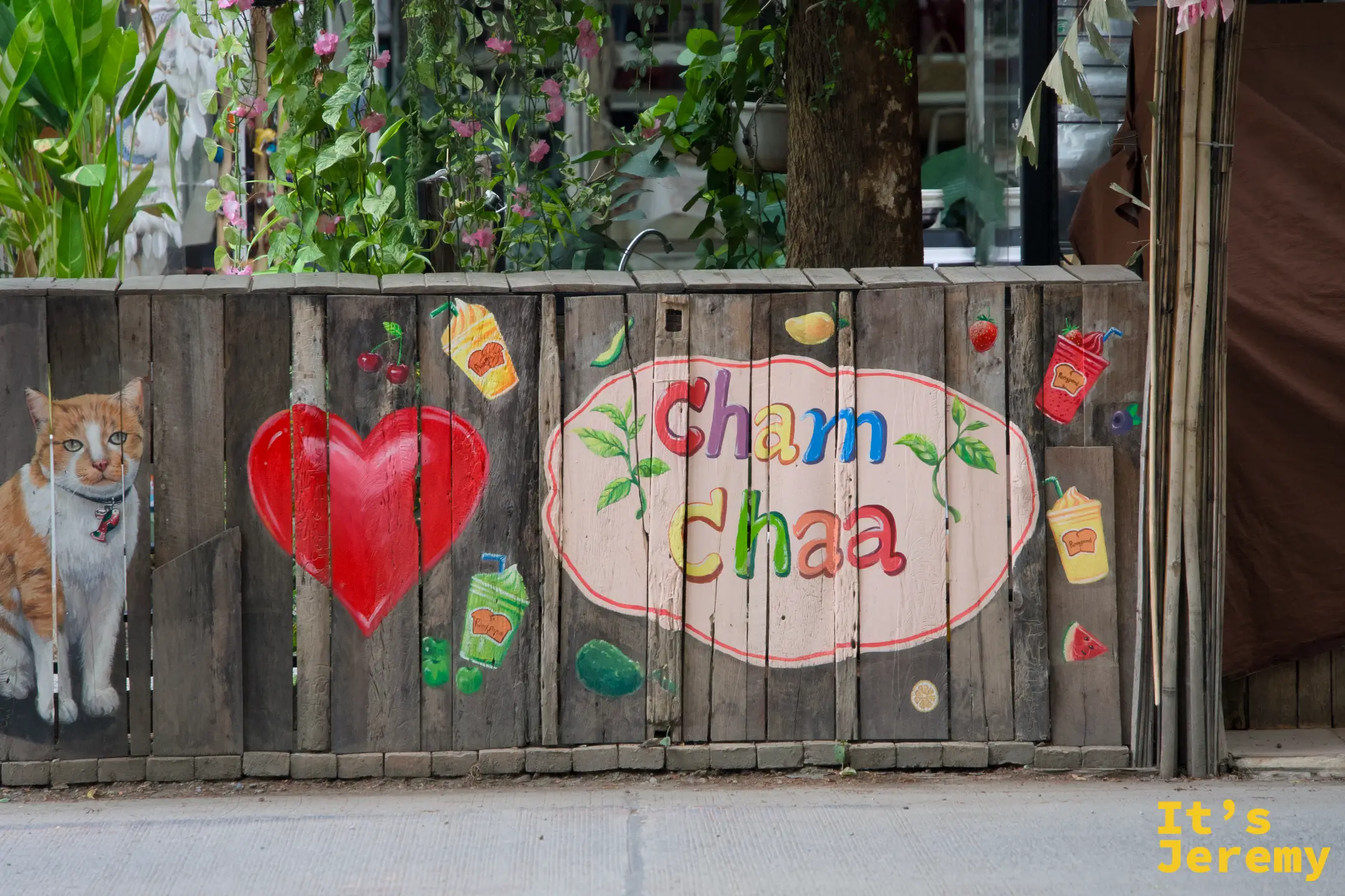 木板牆上的 Cham Chaa 彩繪招牌，旁邊畫著一隻橘貓和大紅愛心