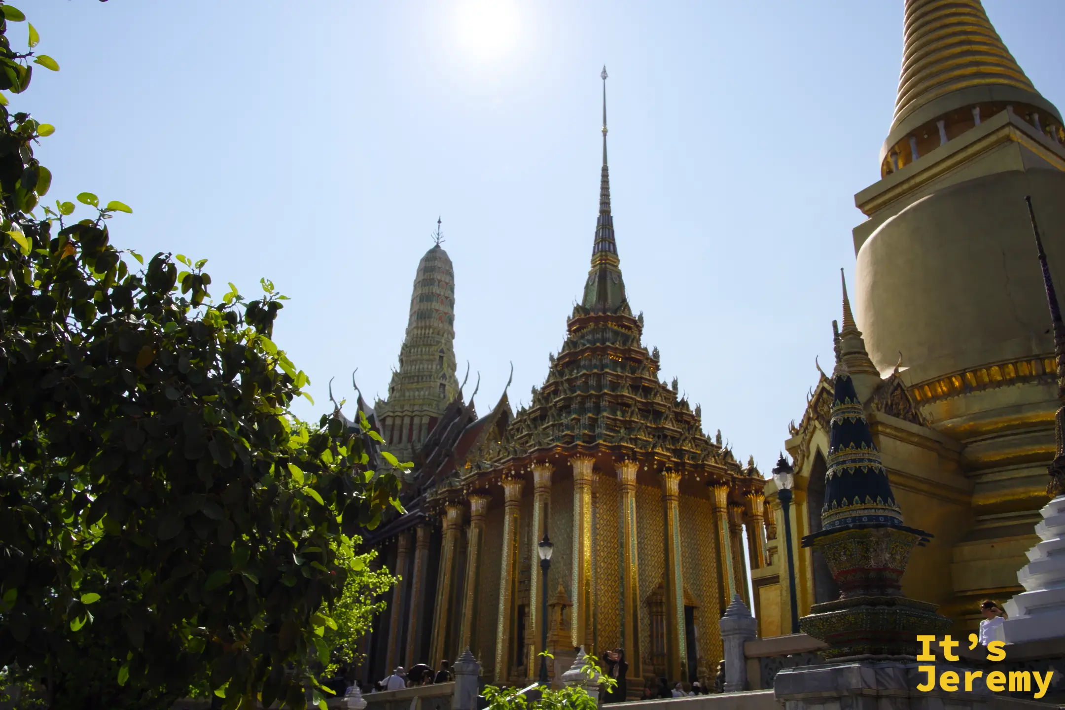 樹蔭前景下的金色 Phra Si Rattana Chedi 與背後彩色 Phra Mondop 藏經閣