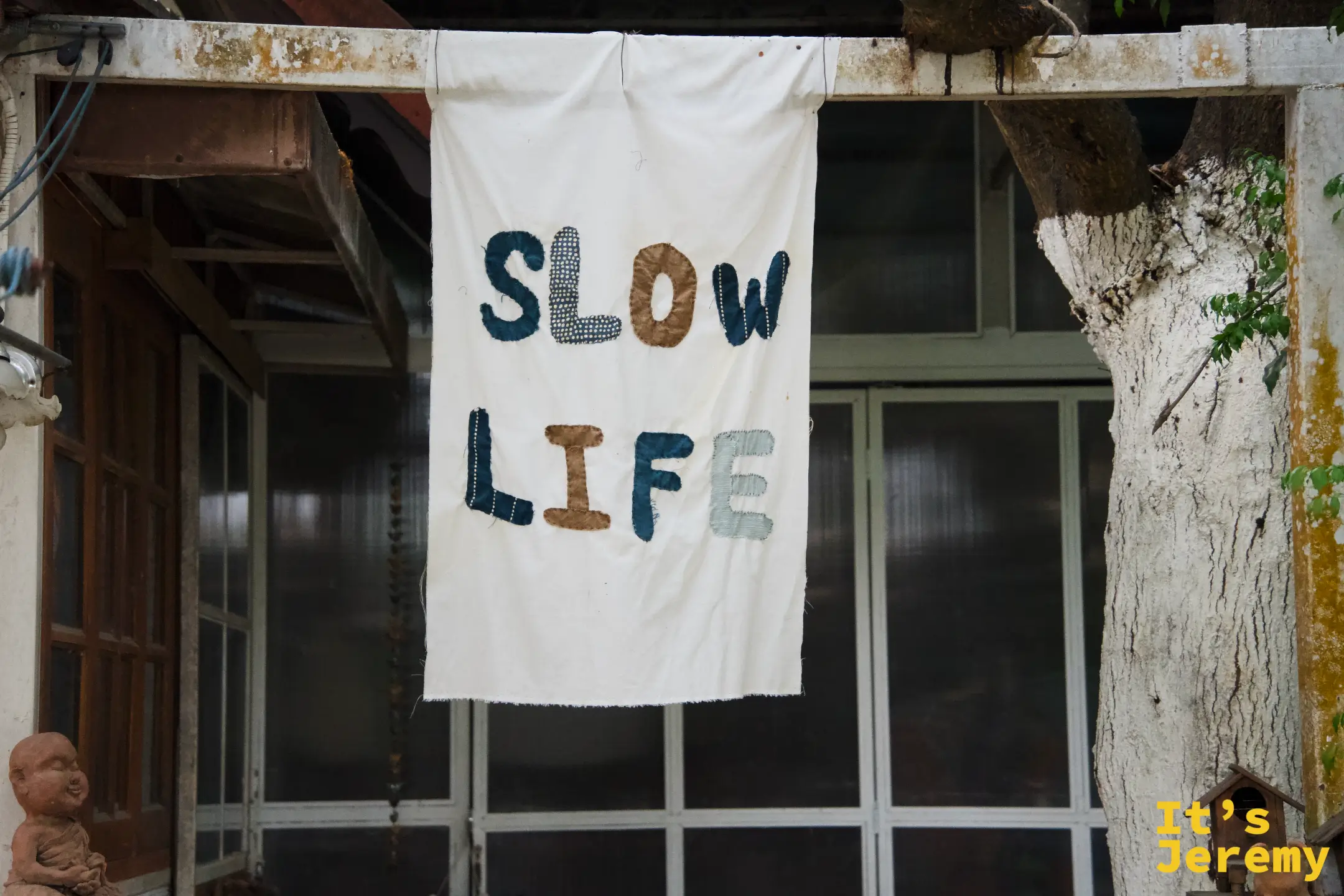 老屋簷下掛著布拼貼的「SLOW LIFE」白布旗