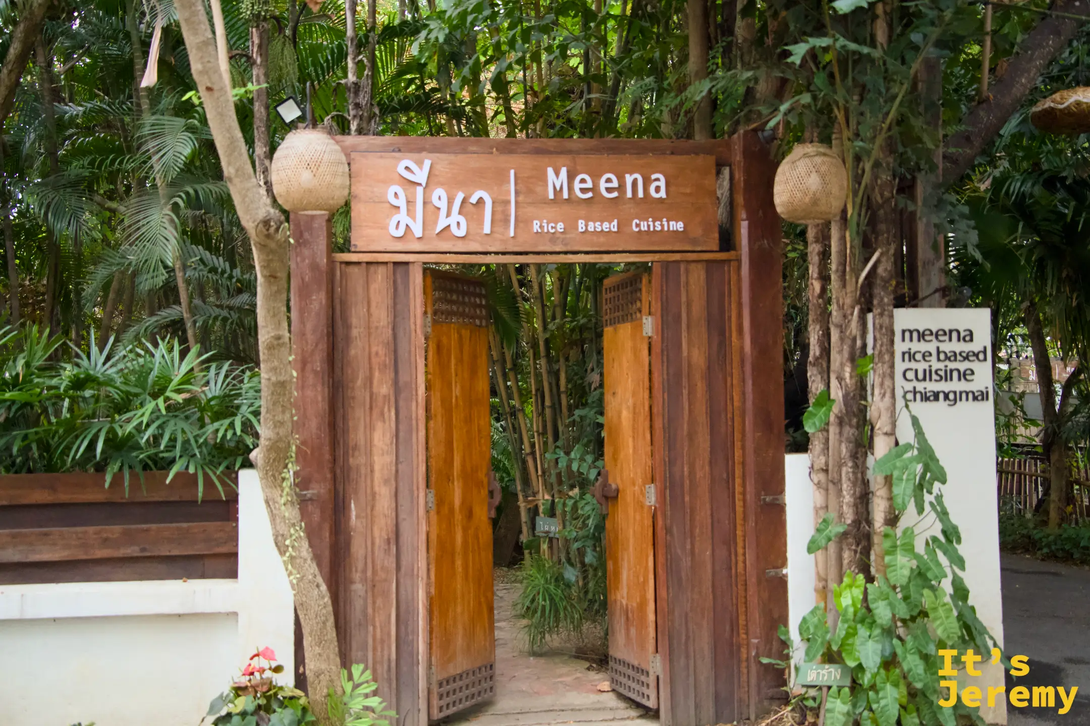 Meena 的木牌坊入口，木雕大門敞開，招牌寫著 มีนา Meena Rice Based Cuisine