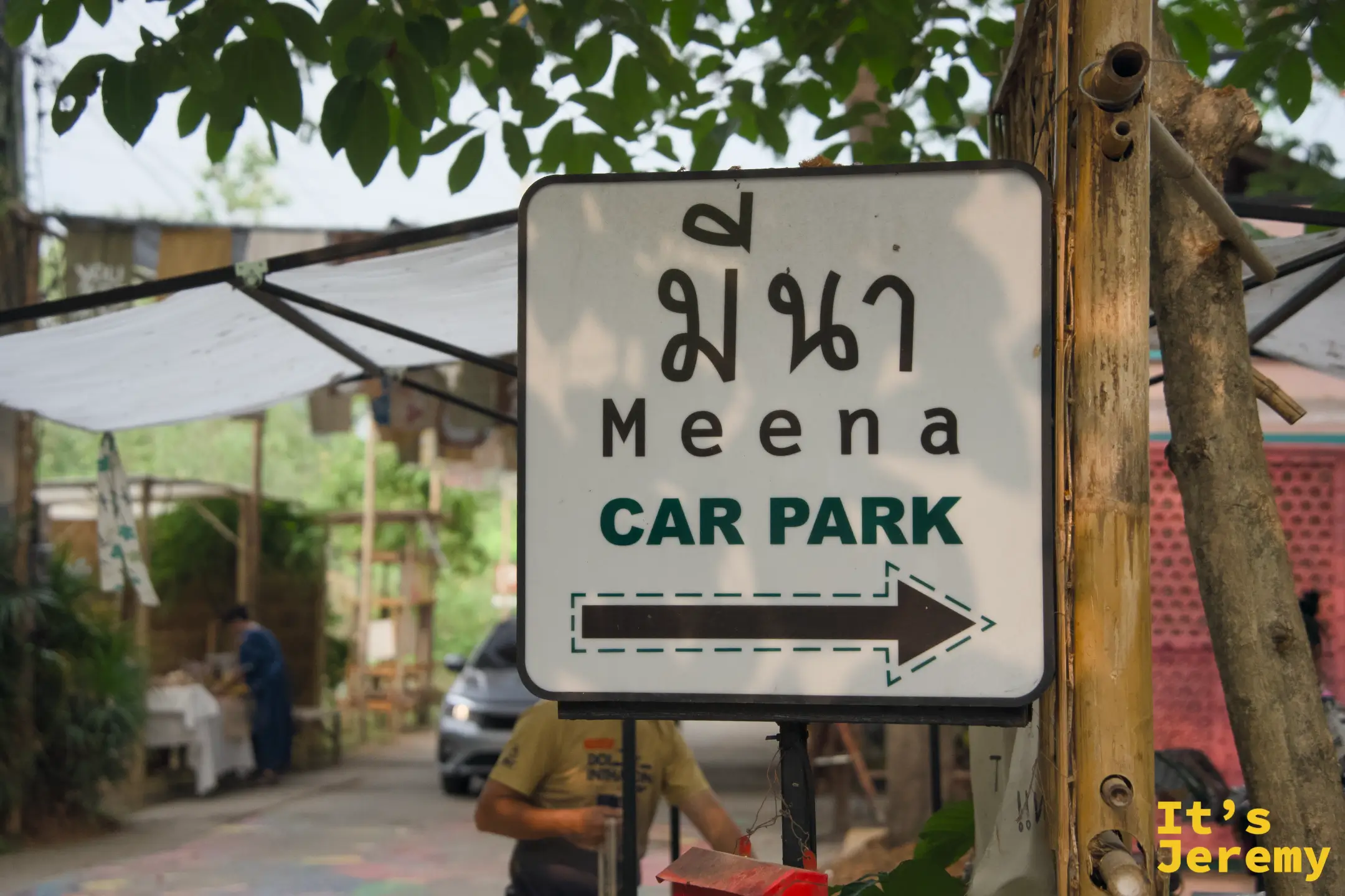 Meena CAR PARK 白色指標牌，咖啡色箭頭指向停車場方向