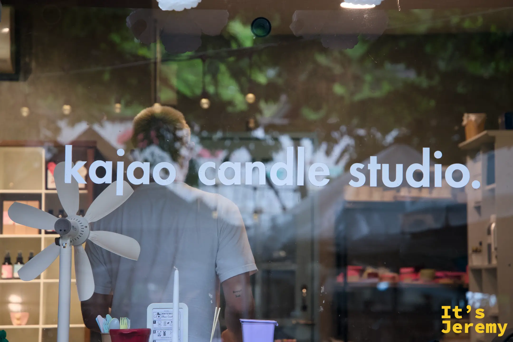 透過玻璃看 kajao candle studio 內部，玻璃上印著店名，映著外面的樹影