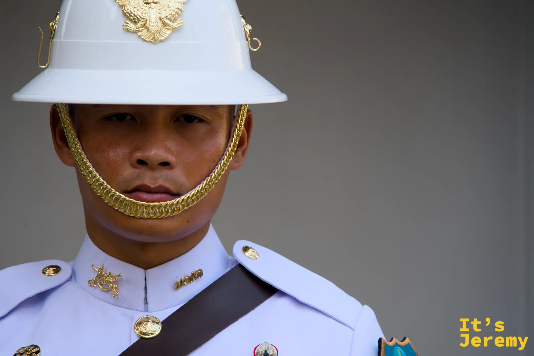皇家衛兵正面特寫：白色制服、白色頭盔上的金色 Garuda 徽章、金鏈下顎帶