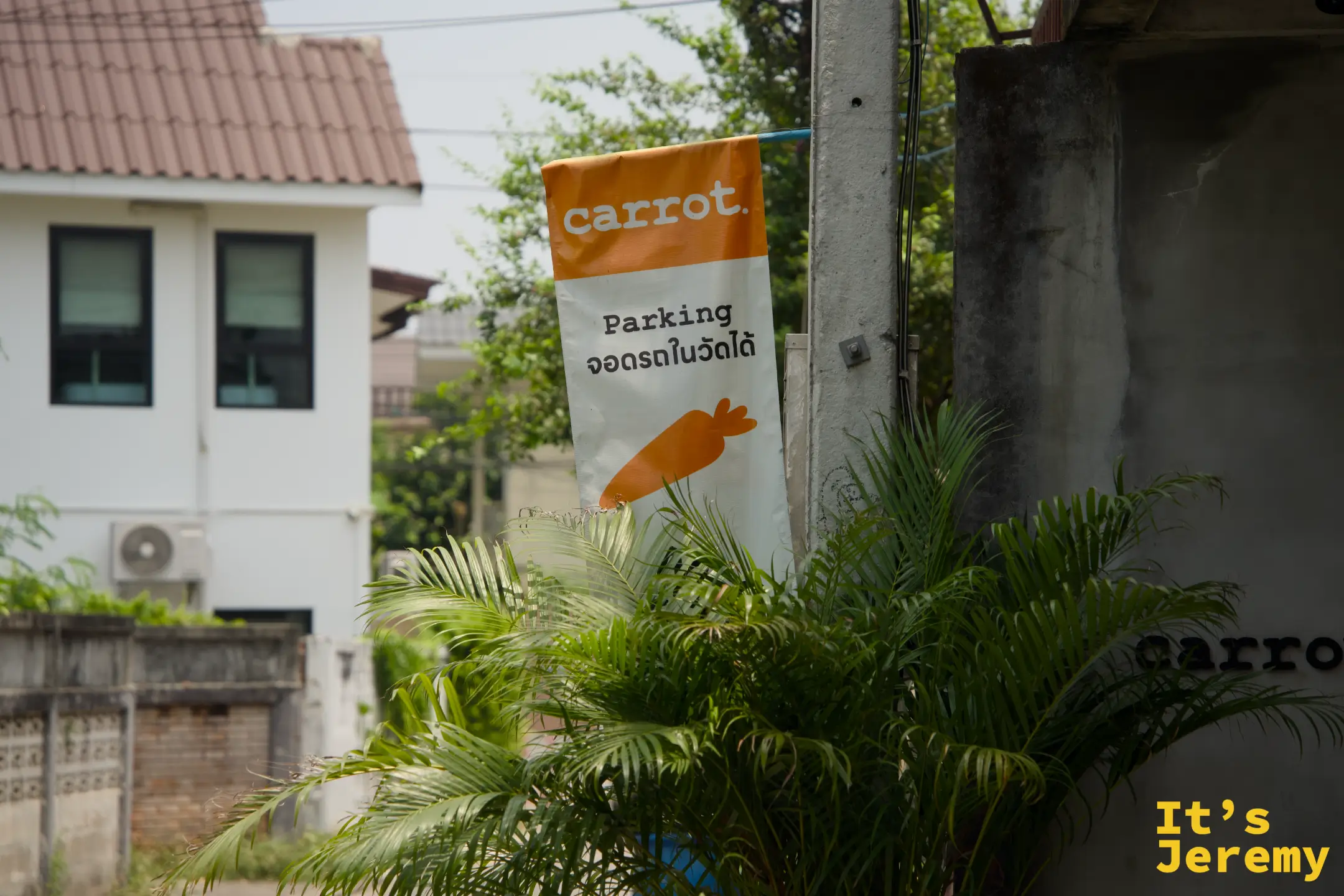 巷口的橘色 carrot 停車旗，寫著可將車停在寺廟內