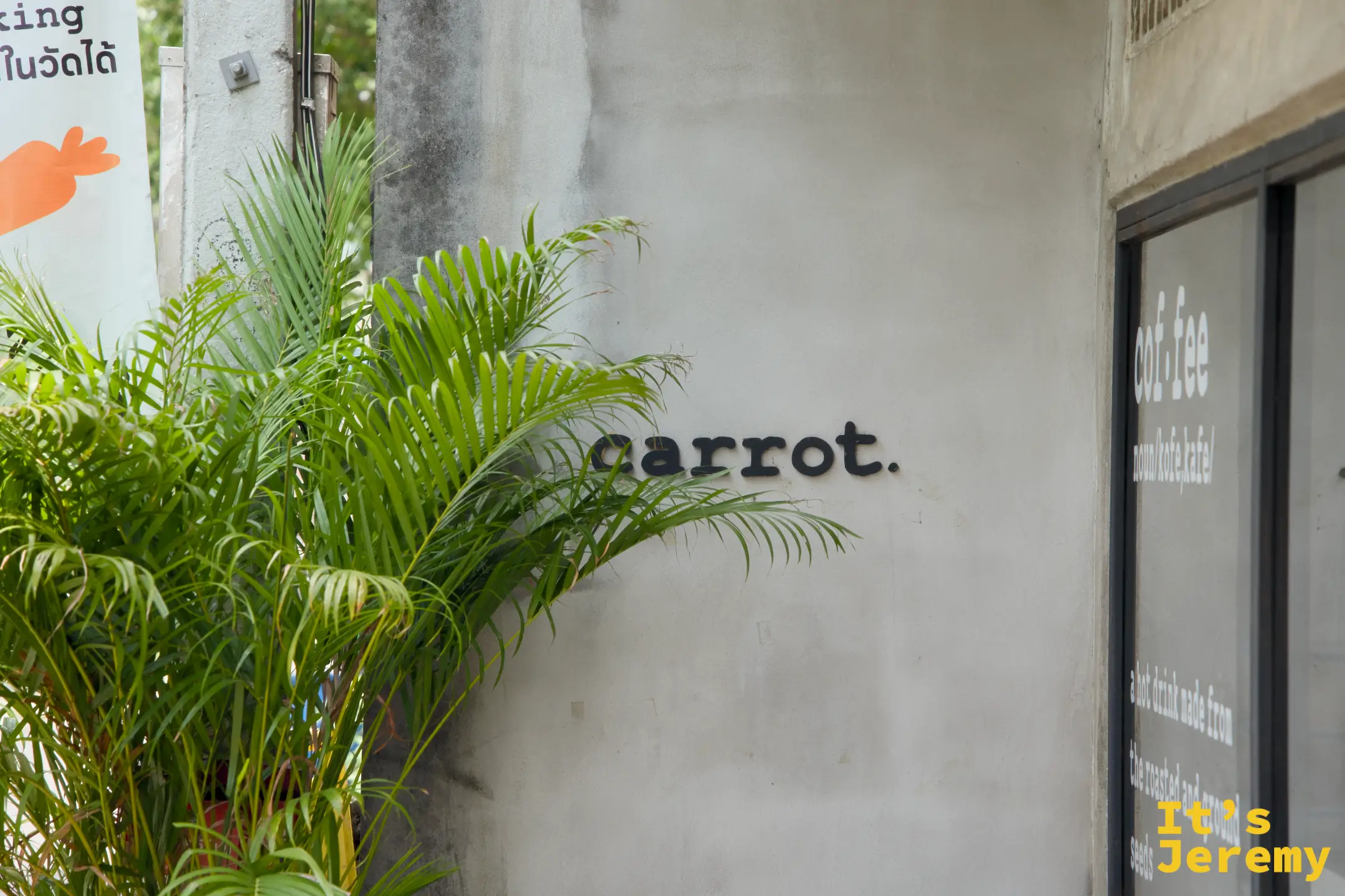 外牆上的 carrot. 字樣與棕櫚盆栽，旁邊就是停車指引旗