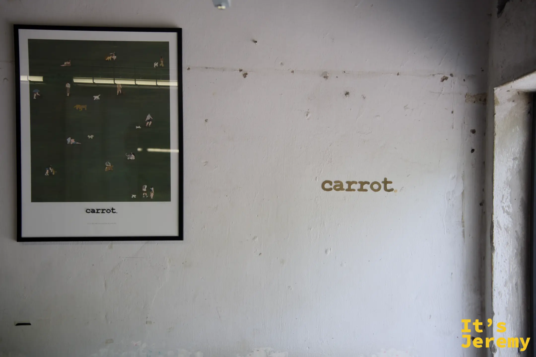 白牆上的金色 carrot. 字樣，旁邊掛著一幅以公園草地為主題的插畫海報