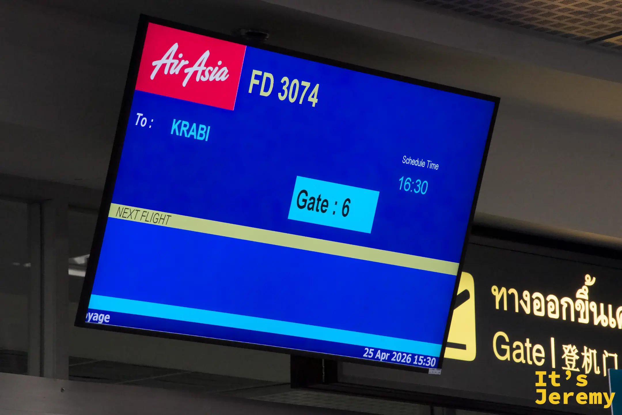 登機門上方的螢幕顯示 AirAsia 飛往喀比的班機資訊，旁邊是黃色的登機門指標