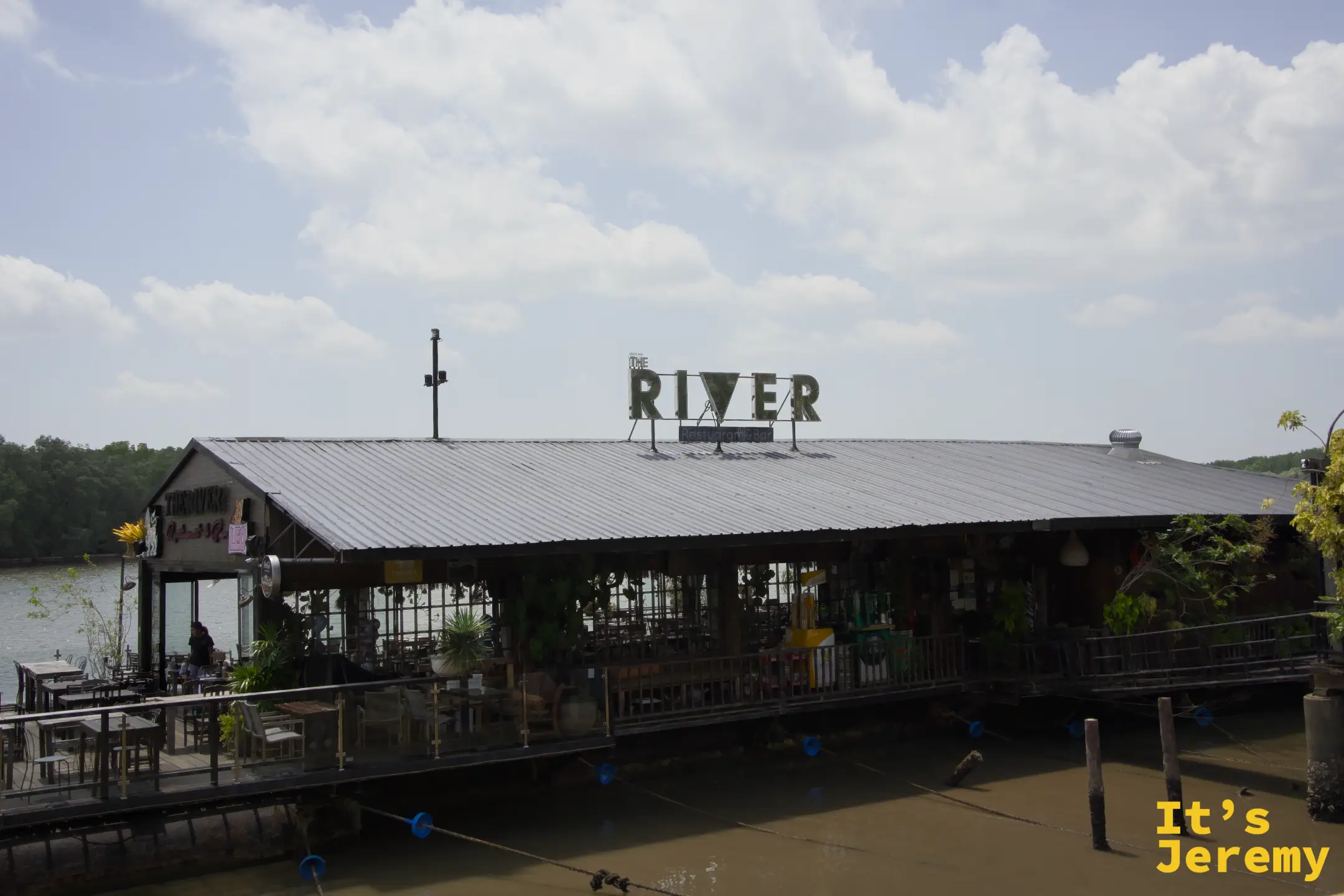 The River 餐廳外觀，屋頂大字招牌，背後是紅樹林
