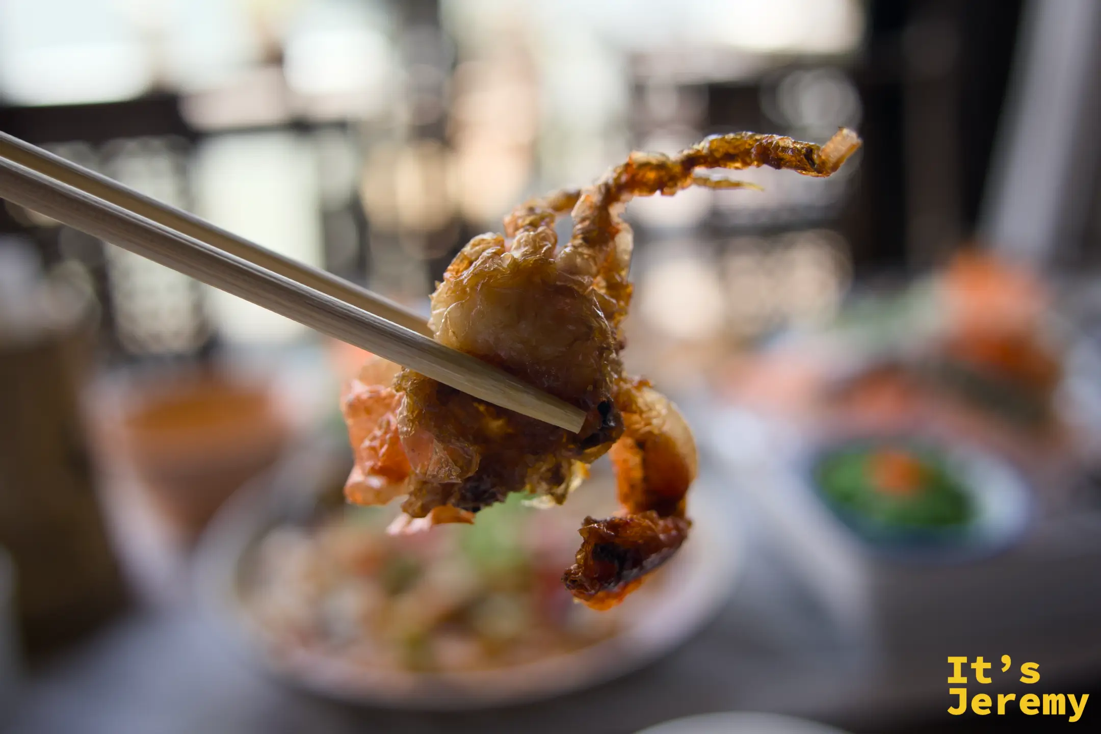 用筷子夾起一塊軟殼蟹，外皮酥脆金黃