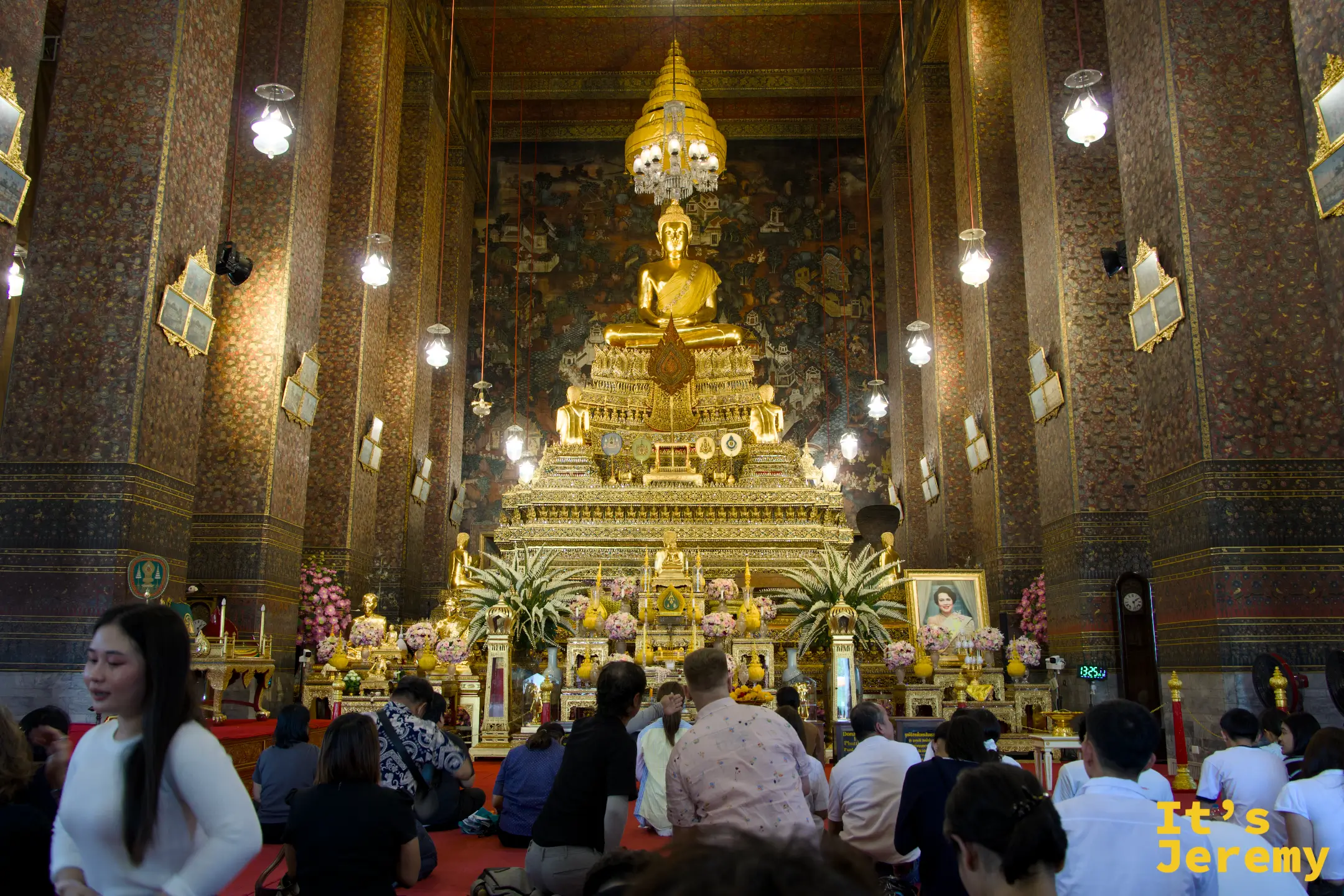 主殿內部全景，金色坐佛 Phra Buddha Deva Patimakorn 高坐台座，信徒跪地禮佛