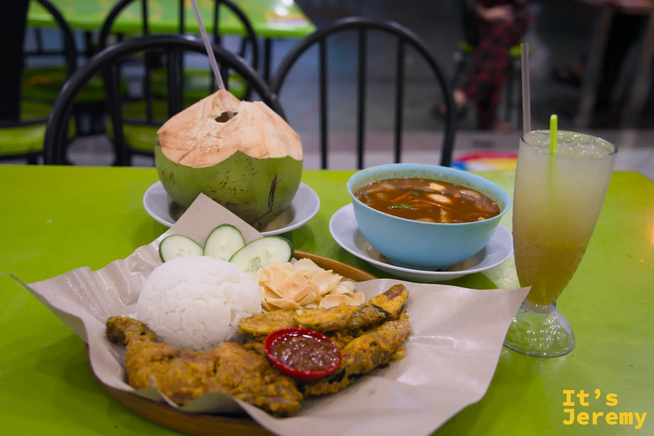 桌上整桌菜俯拍：Nasi Ayam Penyet 炸雞飯、Tomyam 海鮮湯、椰子與蘋果汁