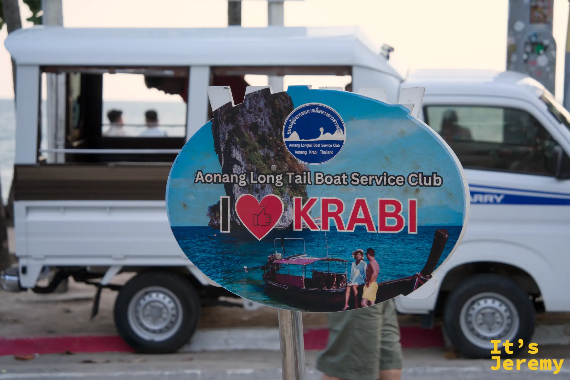Aonang Longtail Boat Service Club 看板，寫著「I ❤ KRABI」，背景是白色廂型車