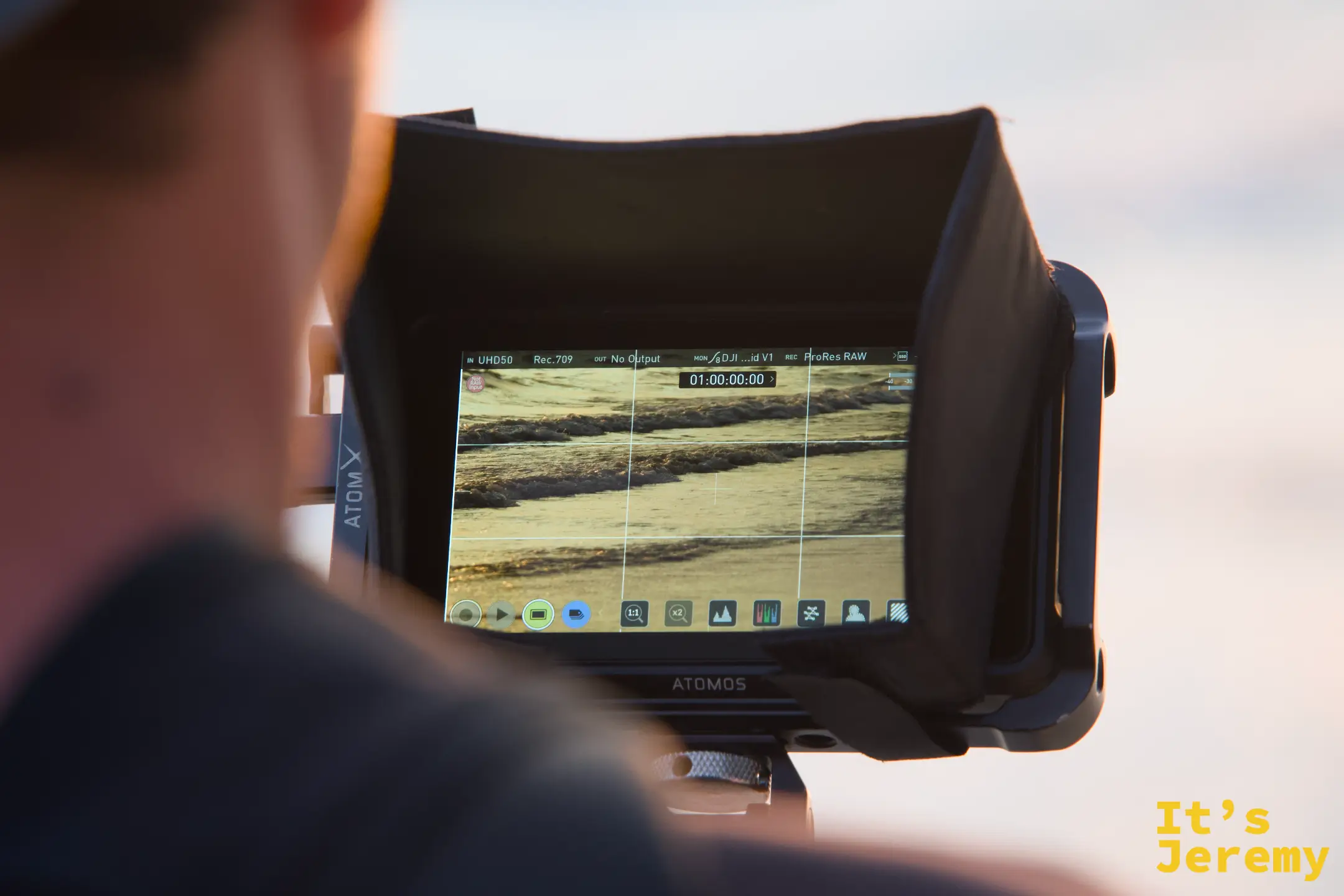一名創作者手持 Atomos 外接螢幕，螢幕上顯示正在拍攝的海浪畫面