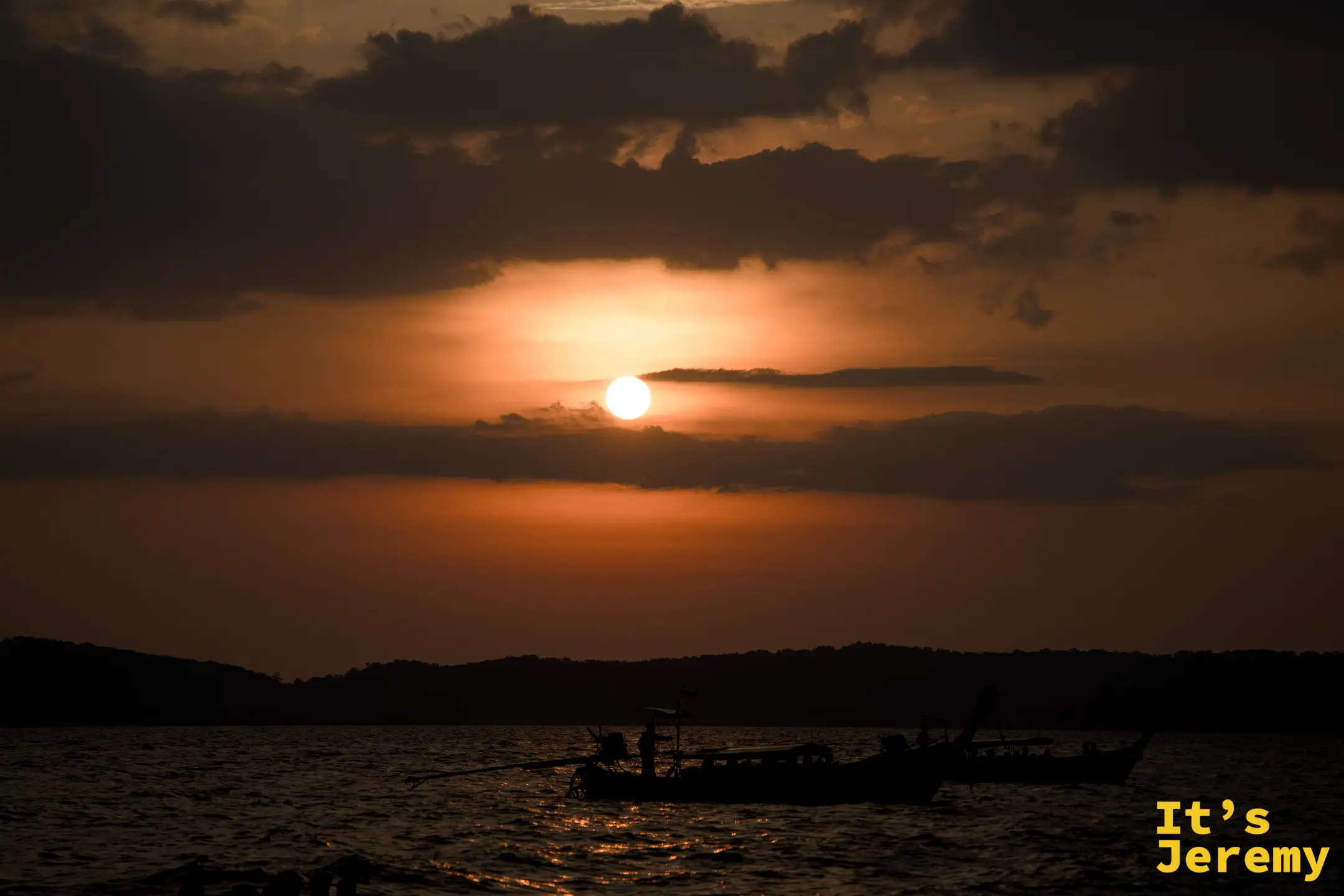 Ao Nang 全橘紅落日，太陽已接近地平線，兩艘小船遠影在寬闊海面上