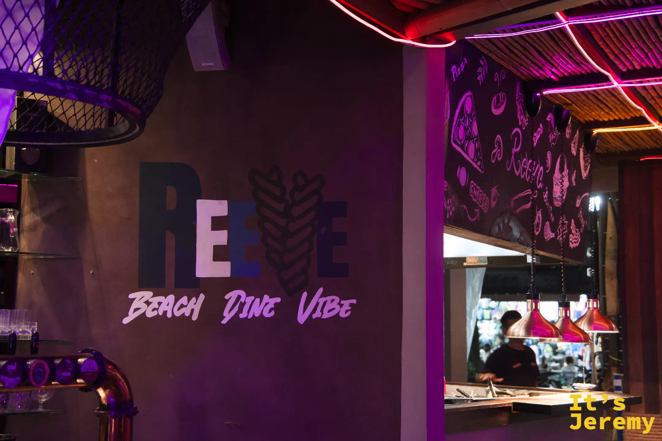 REEVE 室內牆面「Beach Dine Vibe」字樣,紫紅霓虹燈與開放式廚房