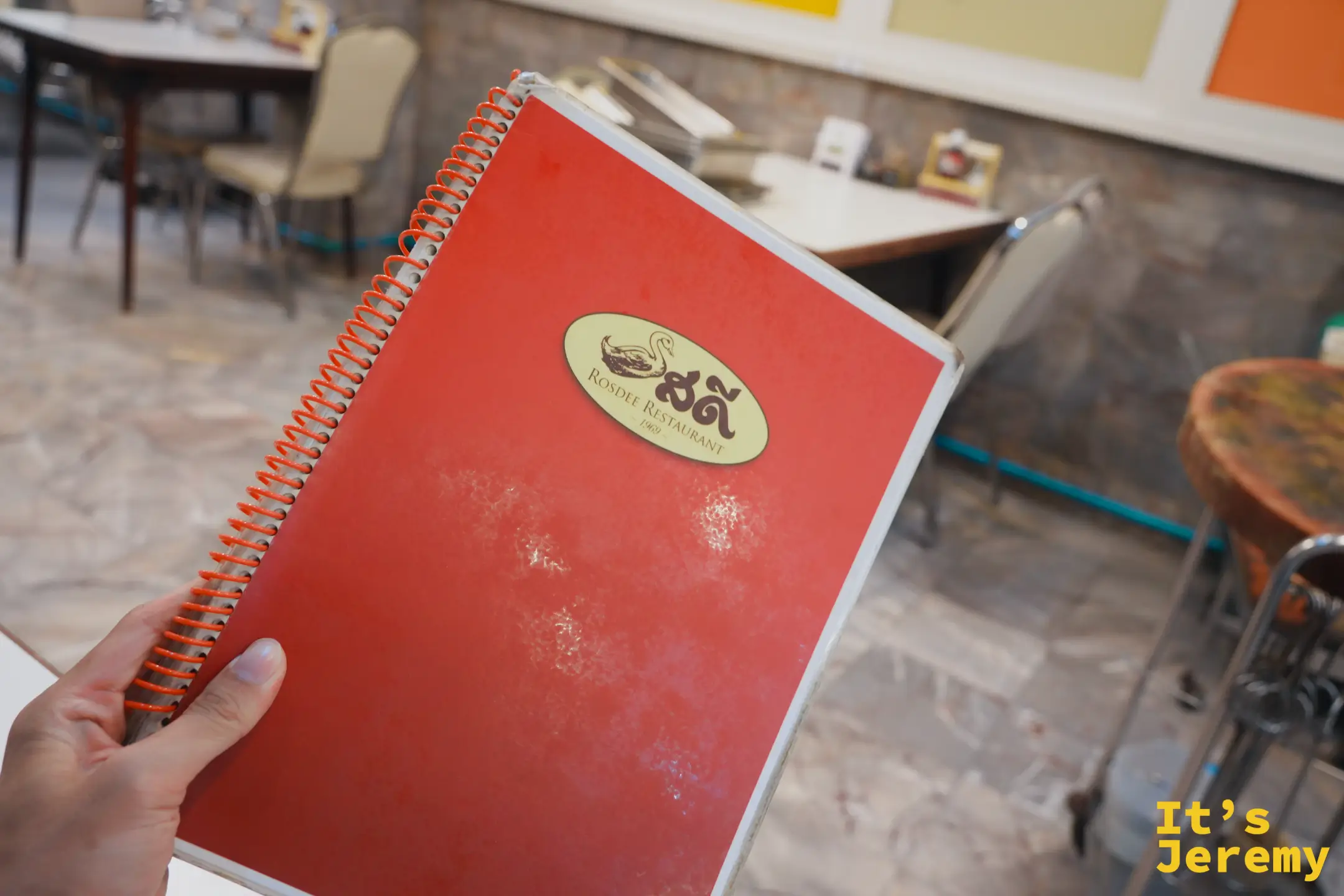 Rosdee Restaurant 橘紅色 spiral-bound 菜單與店內粉色座椅