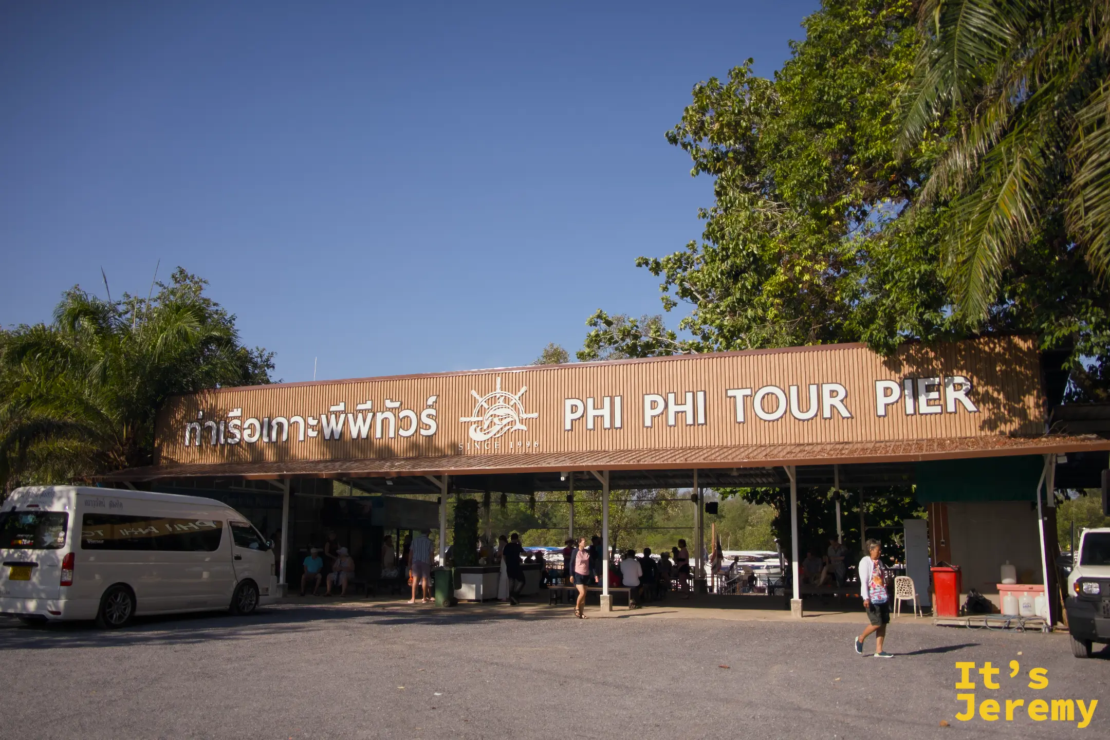 Phi Phi Tour Pier 外觀，停車場有小巴停靠，棚架下是報到與候船區域