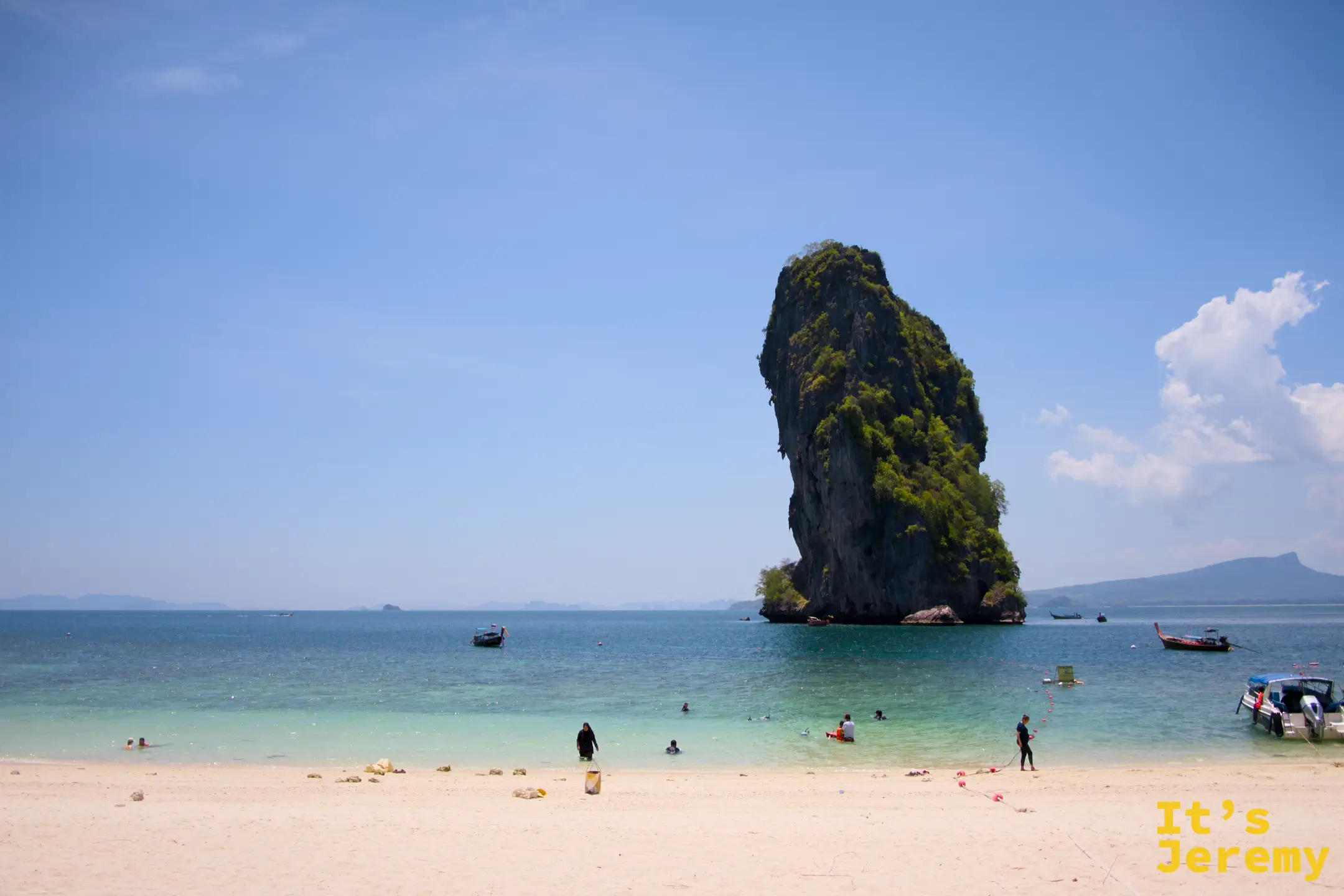 沙灘全景,孤岩與多艘長尾船停靠在岸邊