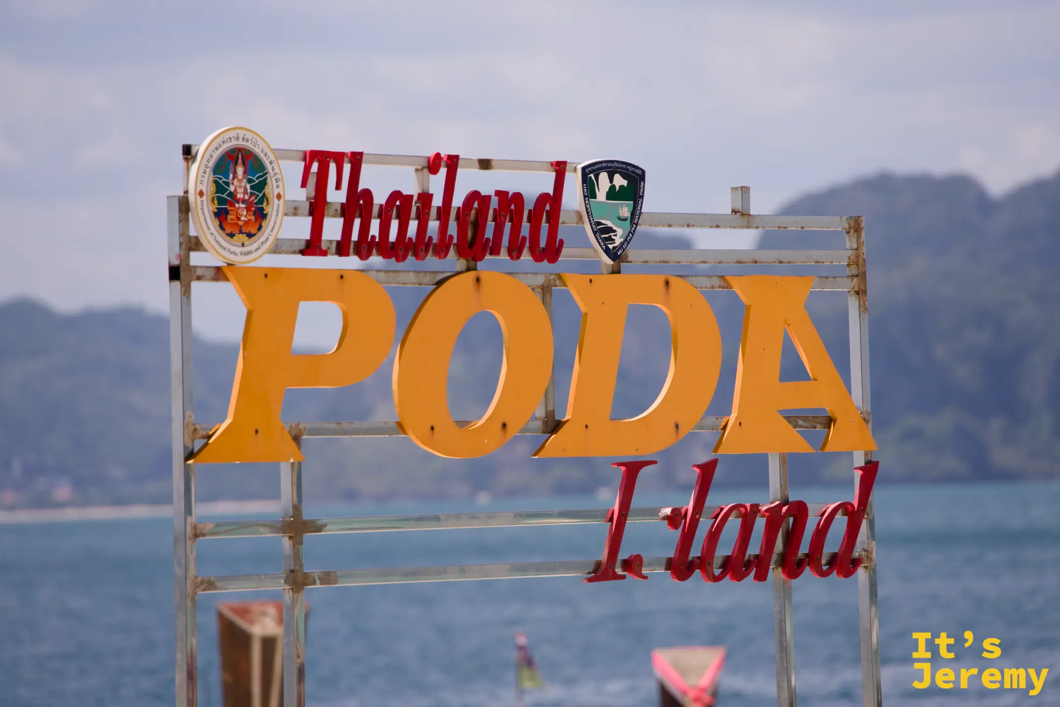 波達島招牌特寫,橘色 PODA 大字清晰可見,背後是喀斯特山脈