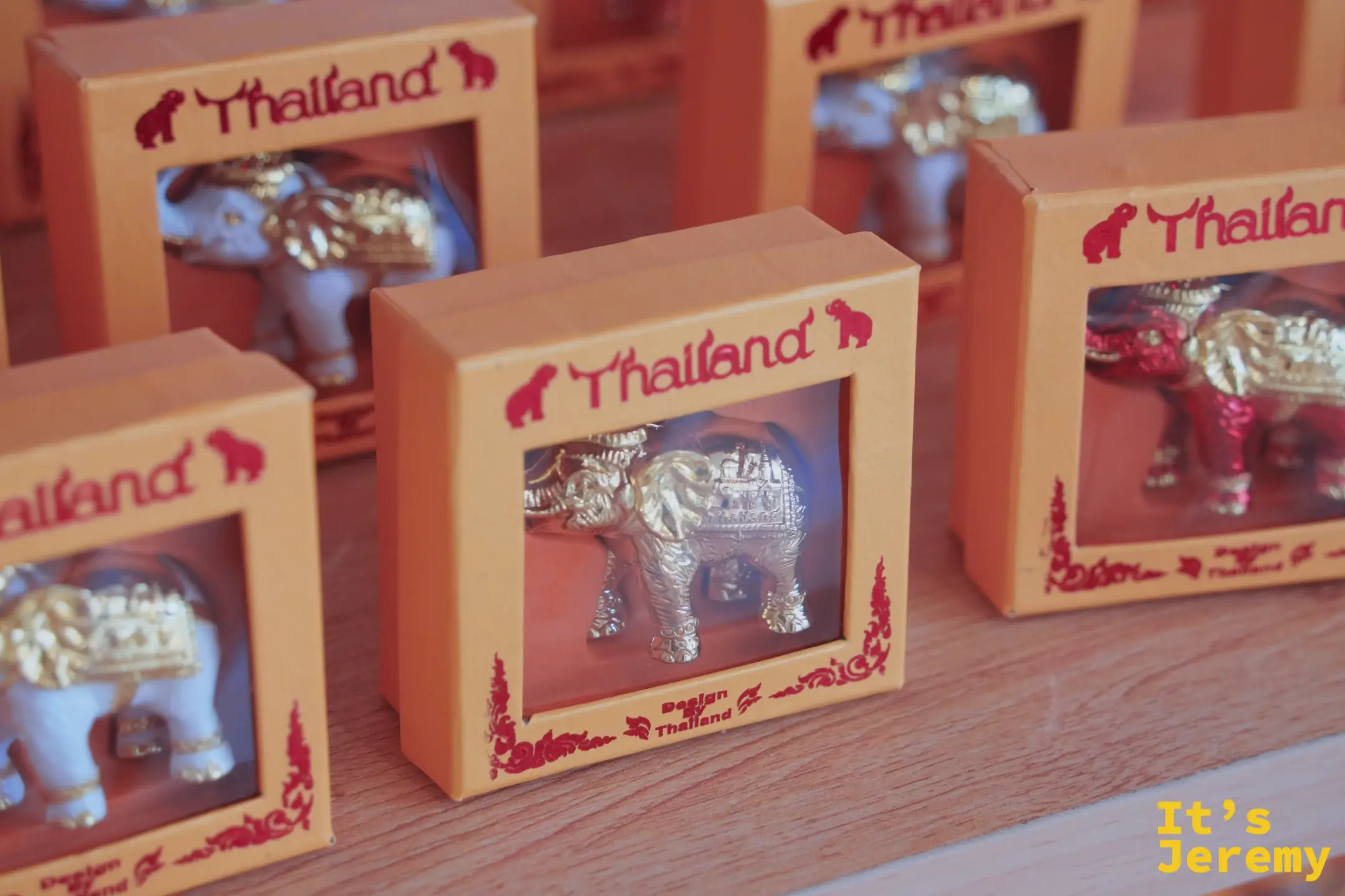 整排「Thailand」字樣的金象紀念盒，紅色泰式邊框