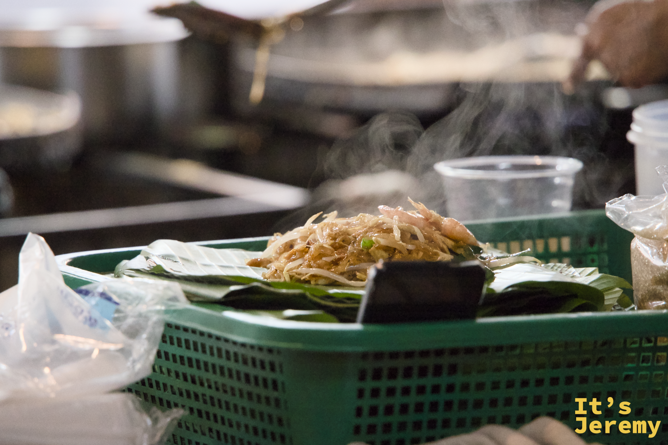 剛炒好的 Pad Thai 盛在芭蕉葉上，豆芽、韭菜和蝦子鋪在米粉頂端，還在冒煙