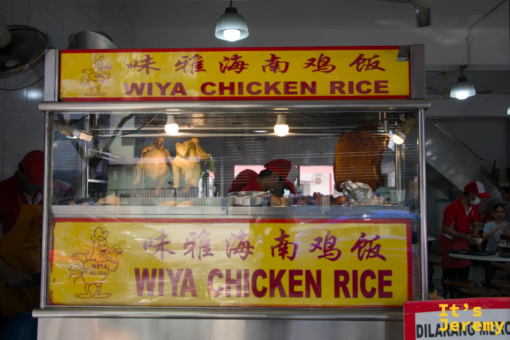 味雅點餐台，整隻雞懸掛在玻璃展示台後，黃底紅字「WIYA CHICKEN RICE」招牌清晰可見