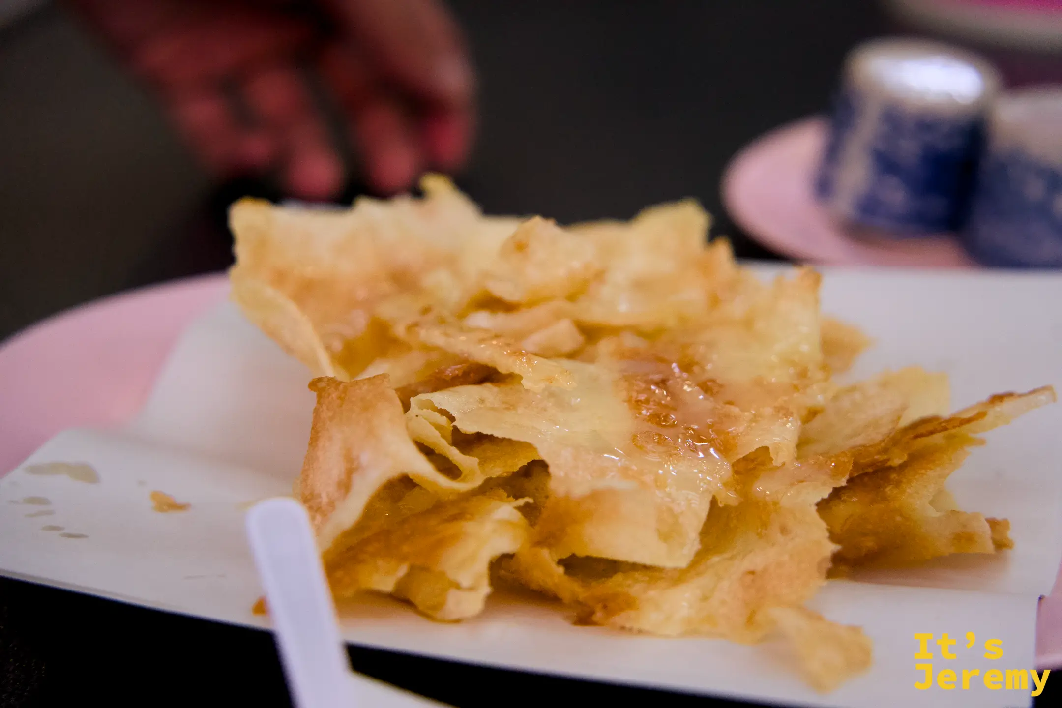 薄脆金黃的 Roti 餅皮堆疊在白色盤上，碎裂邊緣沾著焦糖光澤。
