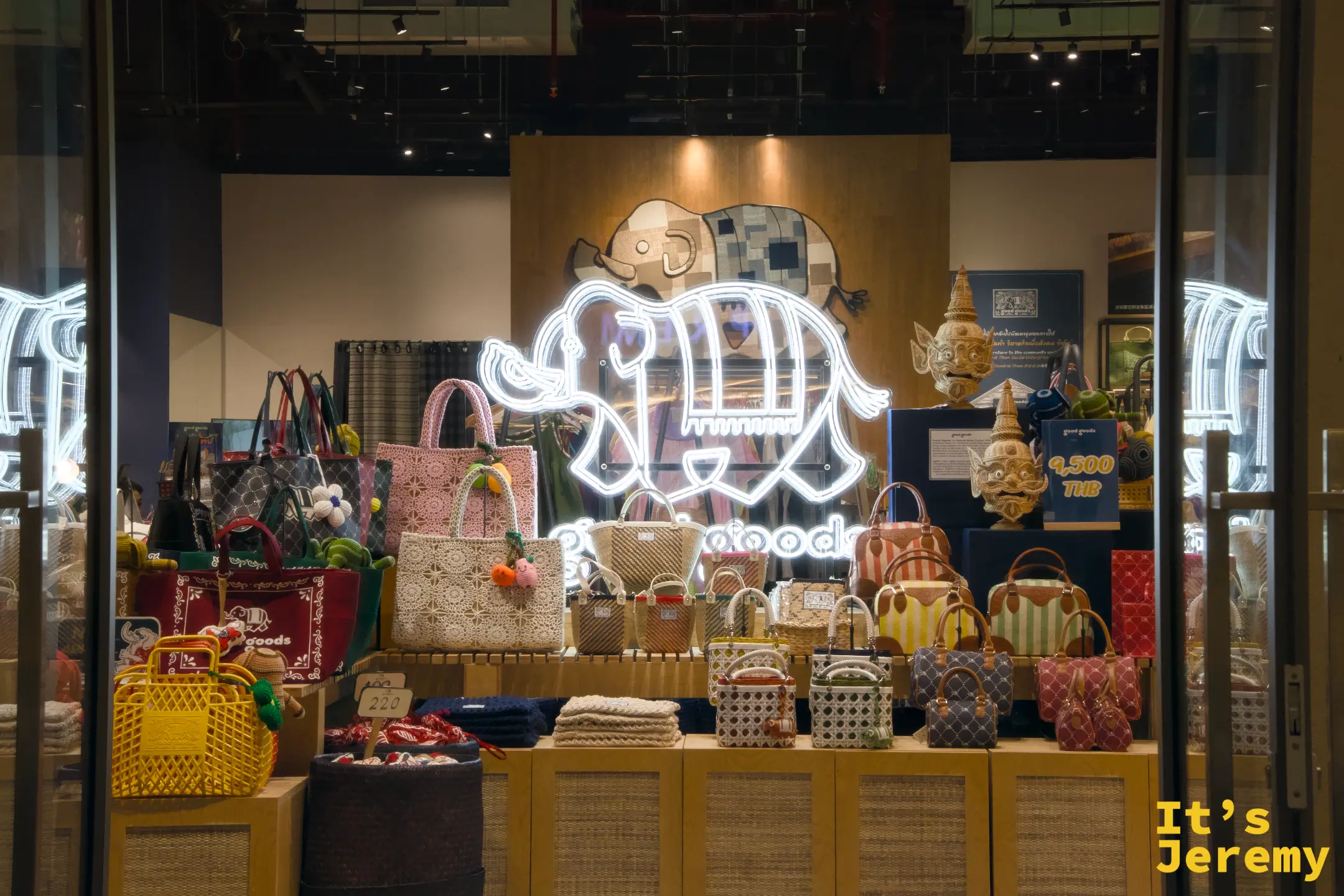 goodgoods 品牌店面櫥窗,展示多款泰式編織包包,背後有大象造型霓虹燈