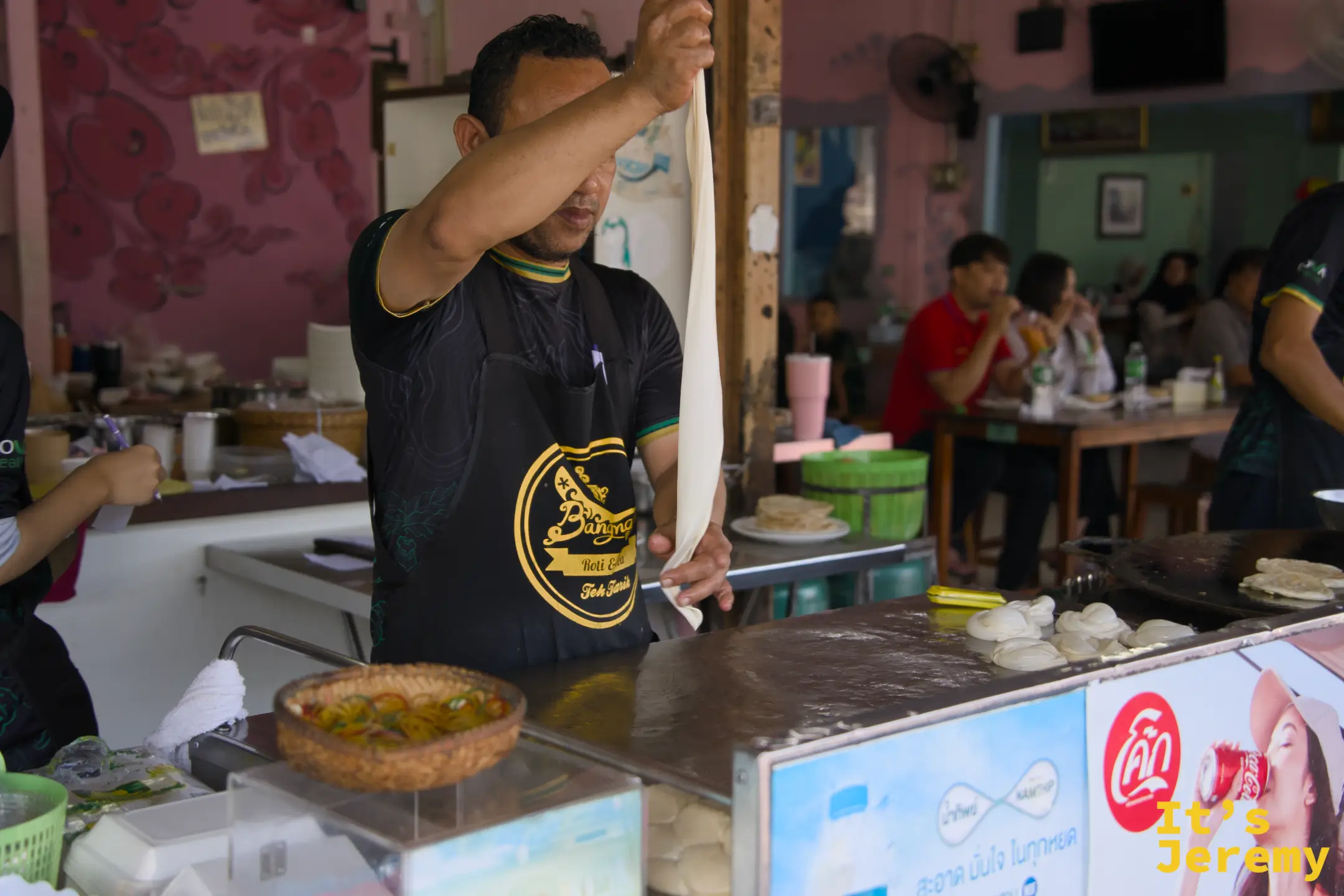師傅將麵糰高舉拉薄，展示 Roti 的製作手法