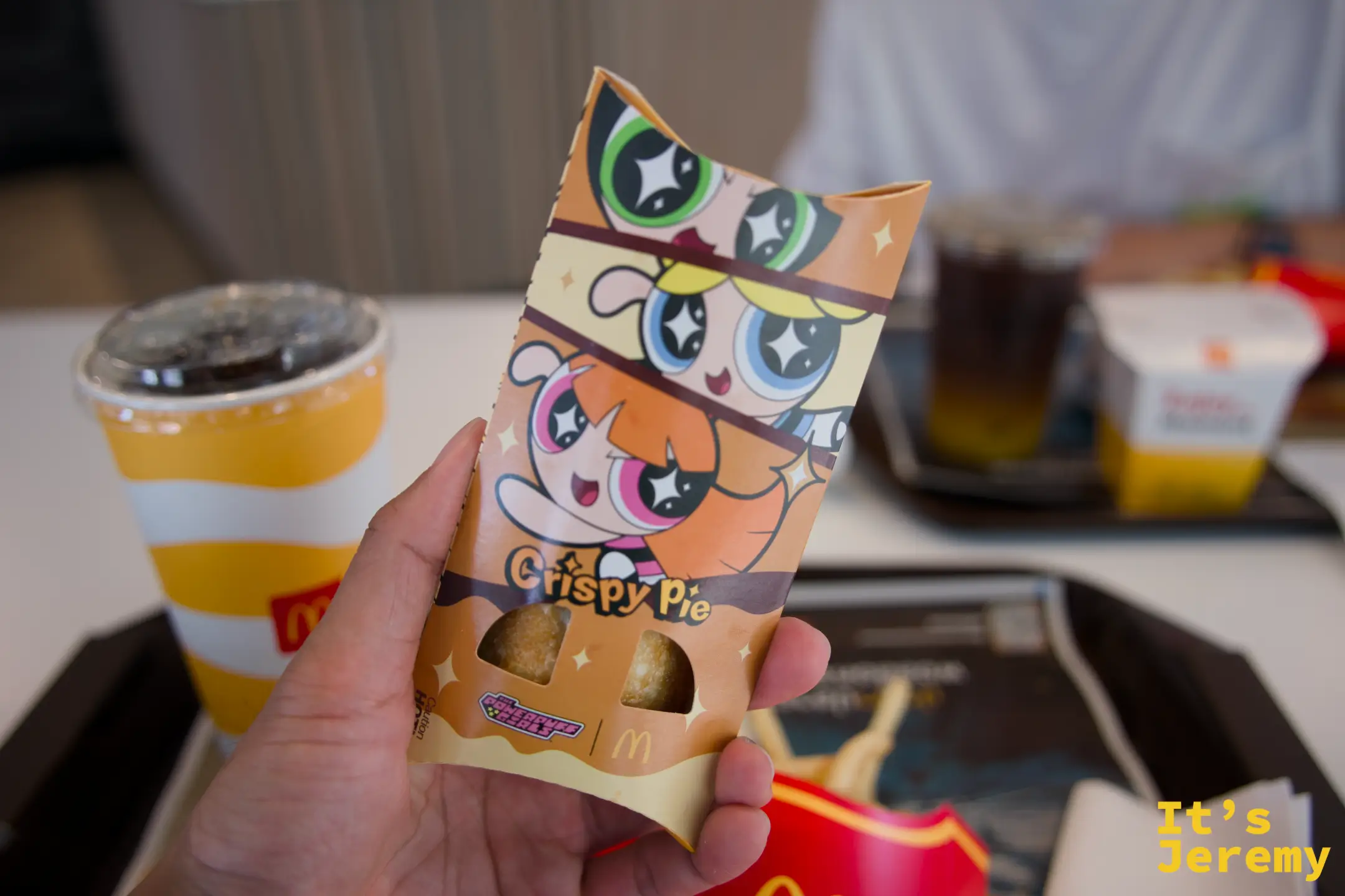 手持麥當勞 Crispy Pie 飛天小女警聯名包裝,橘色紙盒上印著飛天小女警三姐妹圖樣