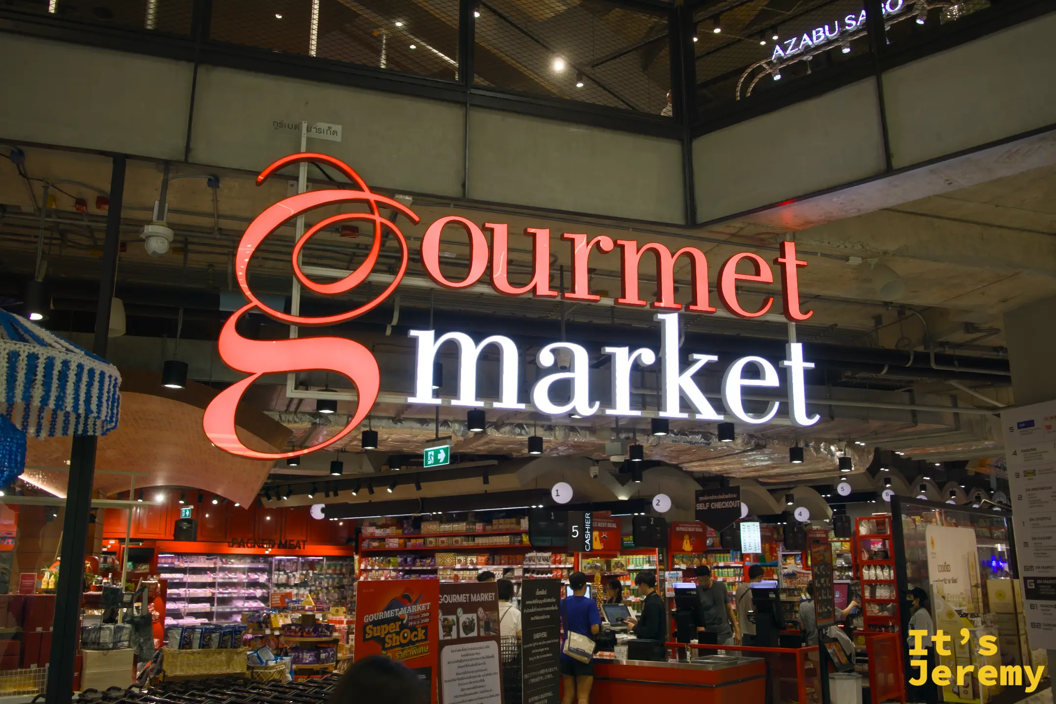 Gourmet Market 招牌特寫,紅色草書 g 字樣,藍色 market 霓虹字,櫃台忙碌中
