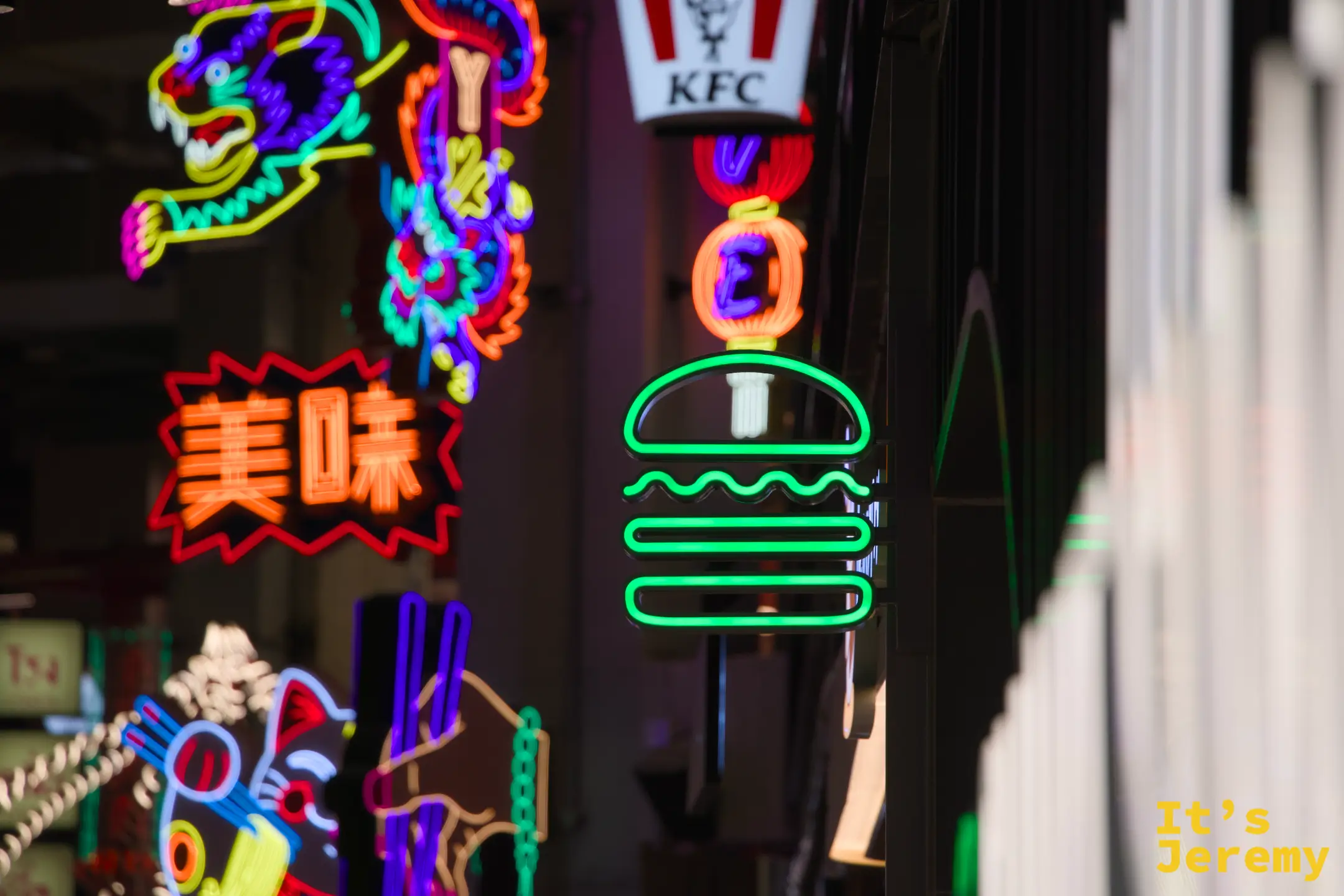 FYI Market 霓虹牆一角，Shake Shack 綠色漢堡霓虹招牌在「美味」紅字燈和 KFC 招牌之間