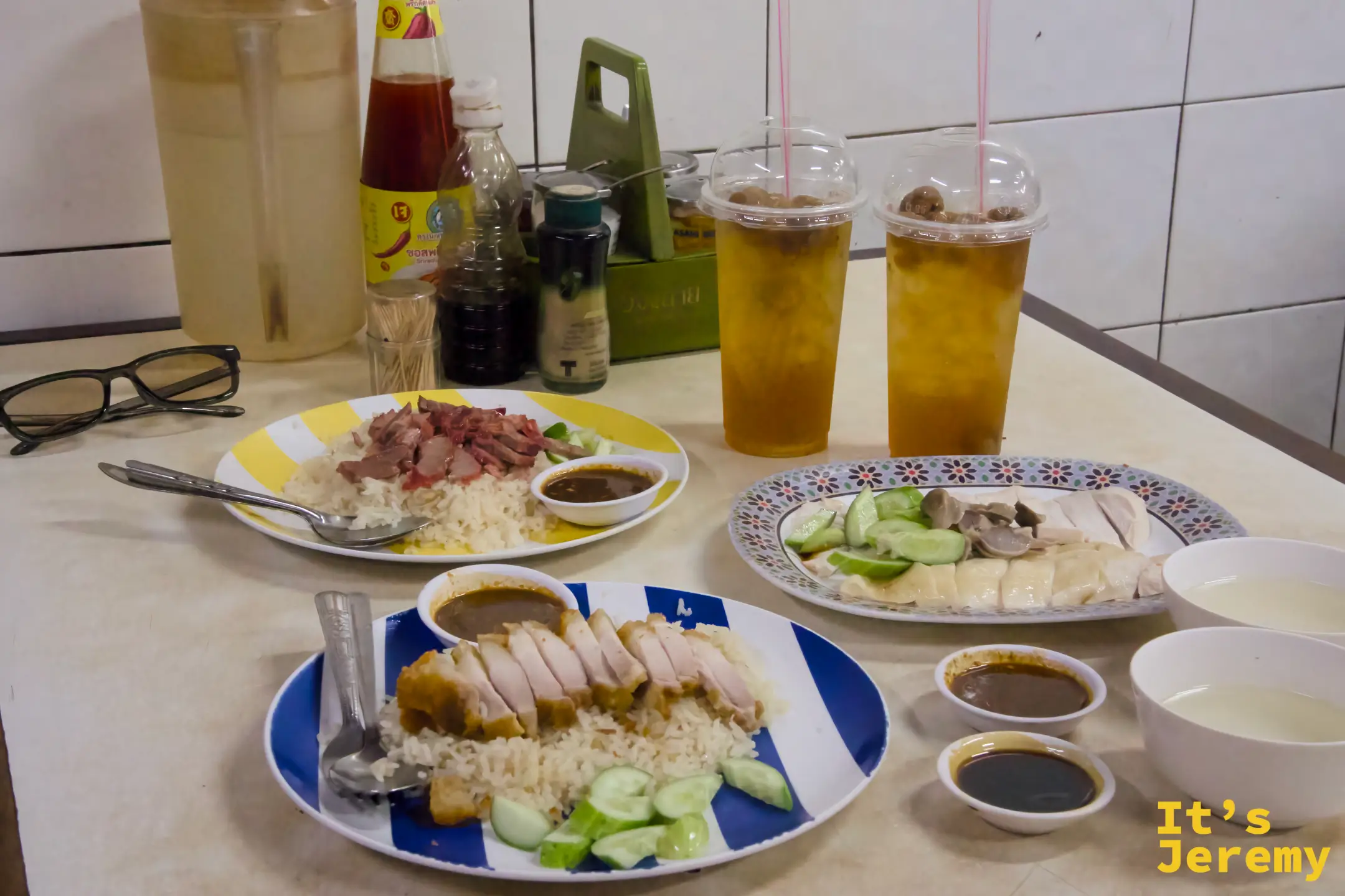 三款配飯同框:脆皮豬、紅燒肉、白斬雞,各附醬汁碗,背景可見調味瓶與兩杯冰飲