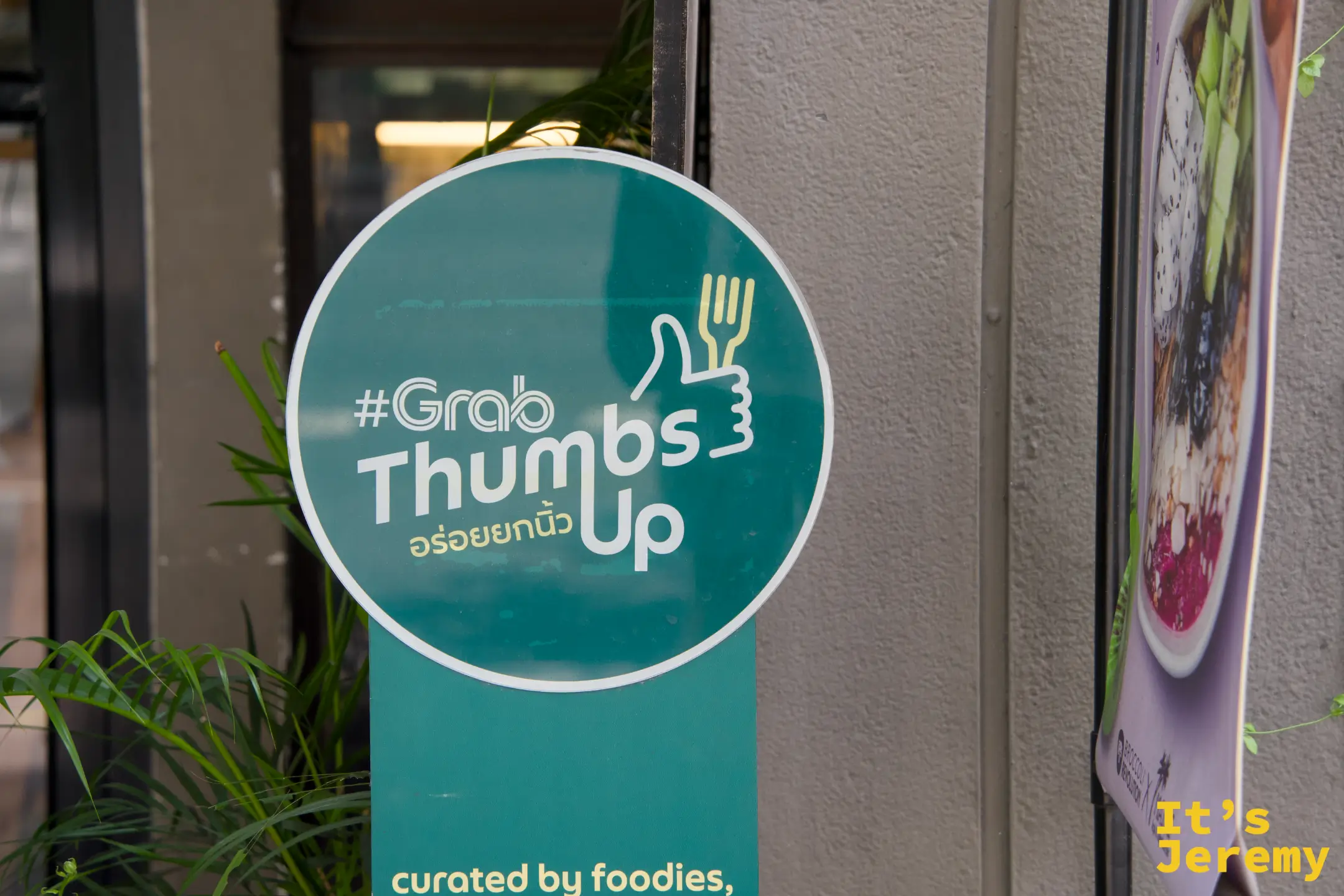 BTS 燈柱上的 GrabFood 貼紙,大拇指朝上,品牌貼紙在曼谷街頭是一種風景