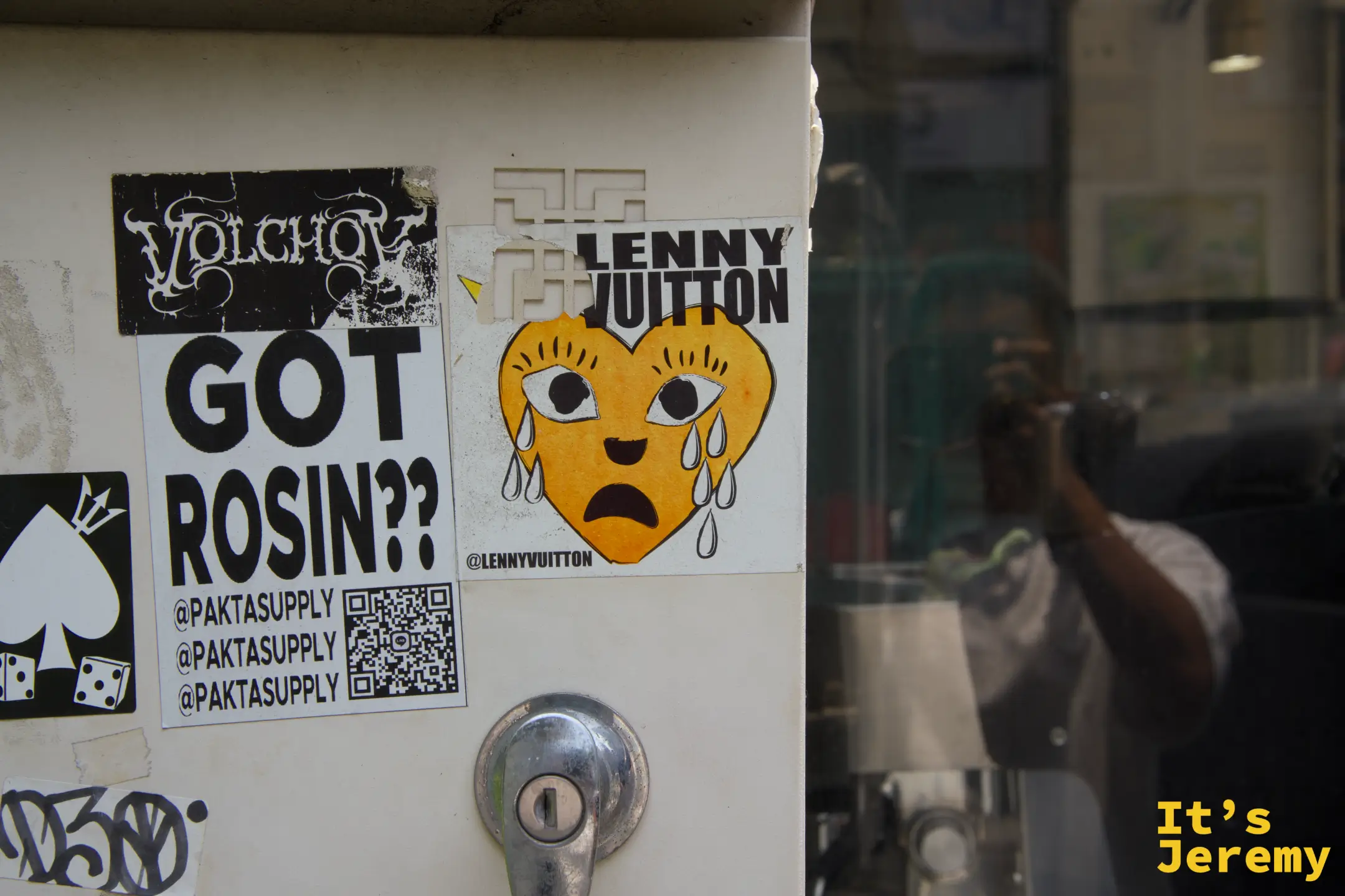 路旁一面佈滿各式街頭貼紙的牆面,"LENNY VUITTON" 的哭臉在其中又出現了一次,像是在 Thonglor 的街頭簽名