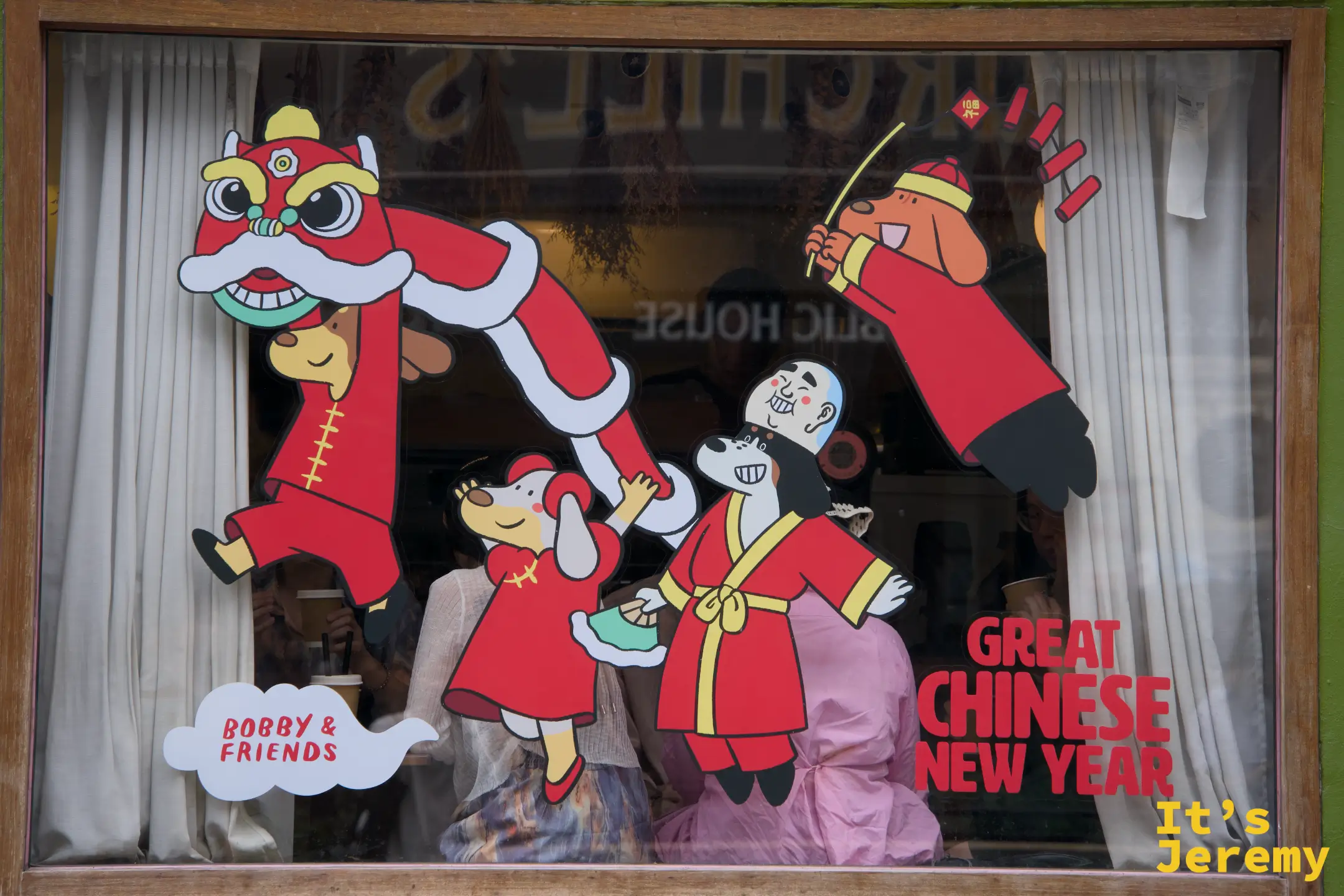 Bobby & Friends 舞獅春節主題的玻璃窗近拍，Bobby 穿唐裝舉鞭炮，色彩濃烈