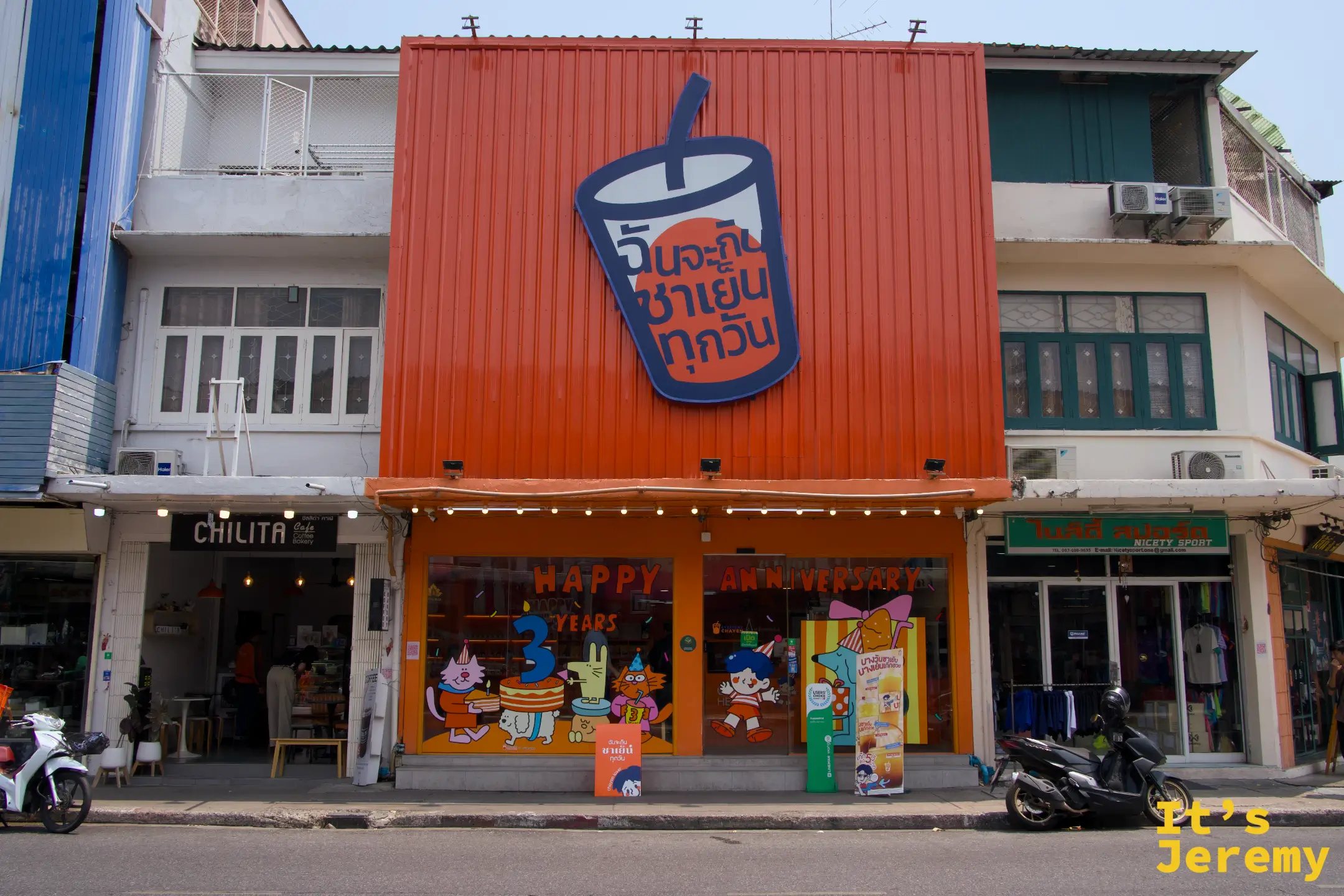Everyday Thai Tea 店外全景，橘色兩層樓建築，店門貼滿 Happy 3 Years Anniversary 的貓兔慶生插圖