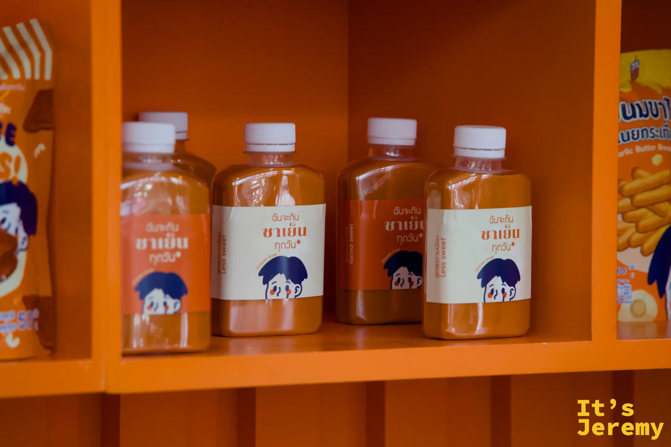 展示架上的瓶裝泰式冰茶，標示 Less Sweet 與 Normal Sweet，背景是橘色展示格