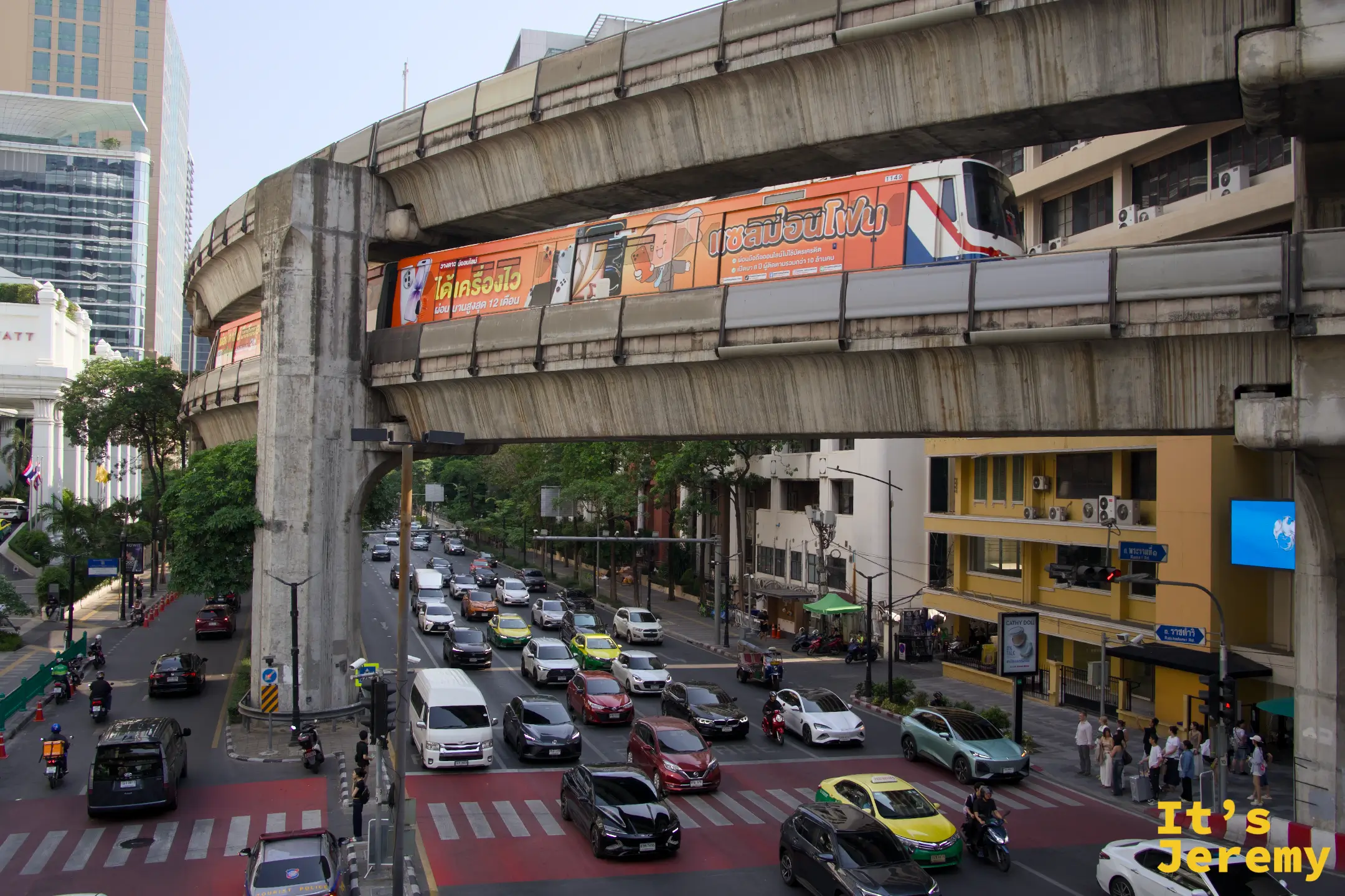 從更高的視角俯拍 BTS Siam 站一帶,電聯車正在進站,下方路口同時塞著幾十輛車,城市密度在這個角度裡壓縮成一張平面
